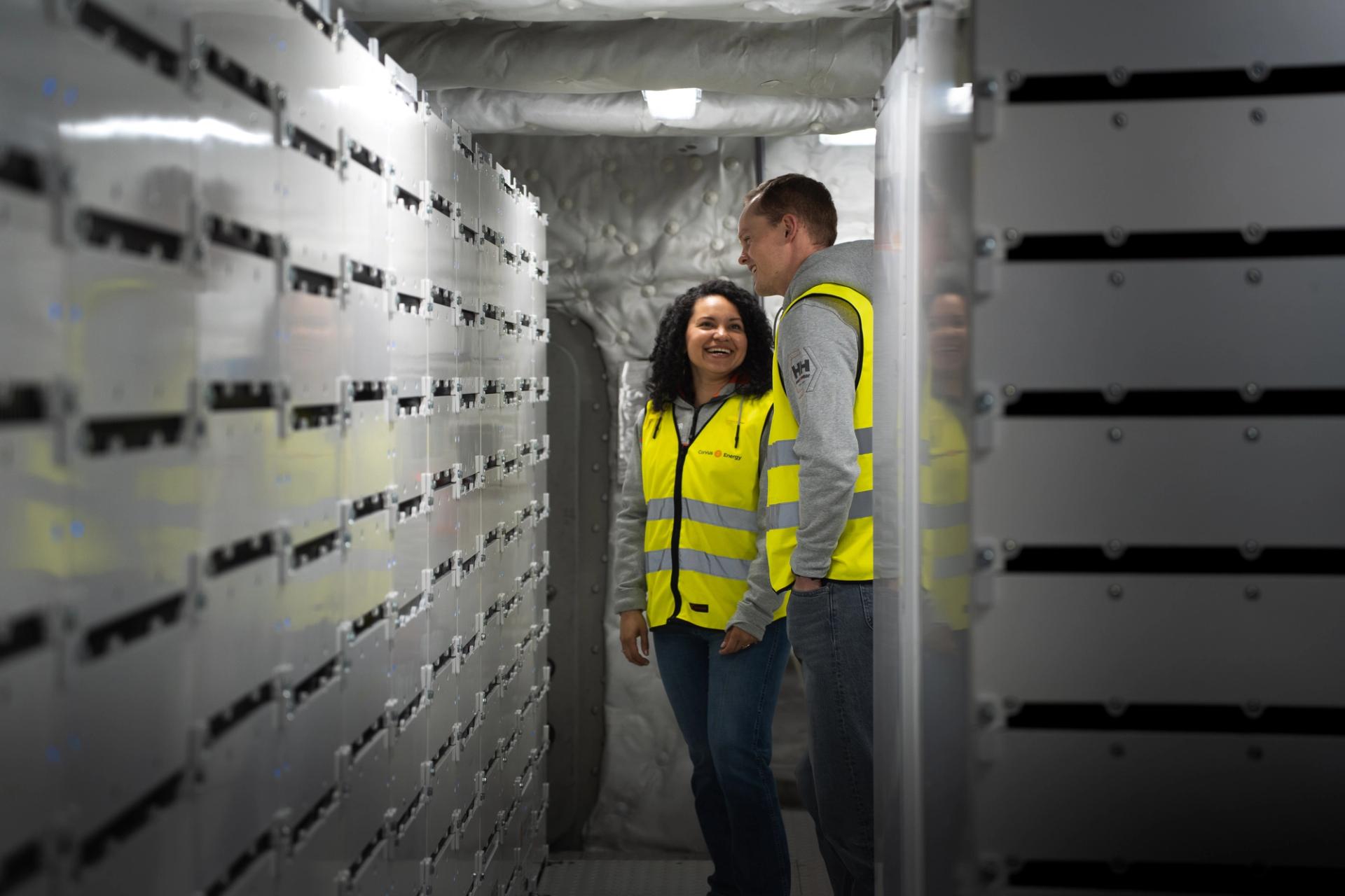 A man and a woman in high visibility vests examining energy storage systems in a boat