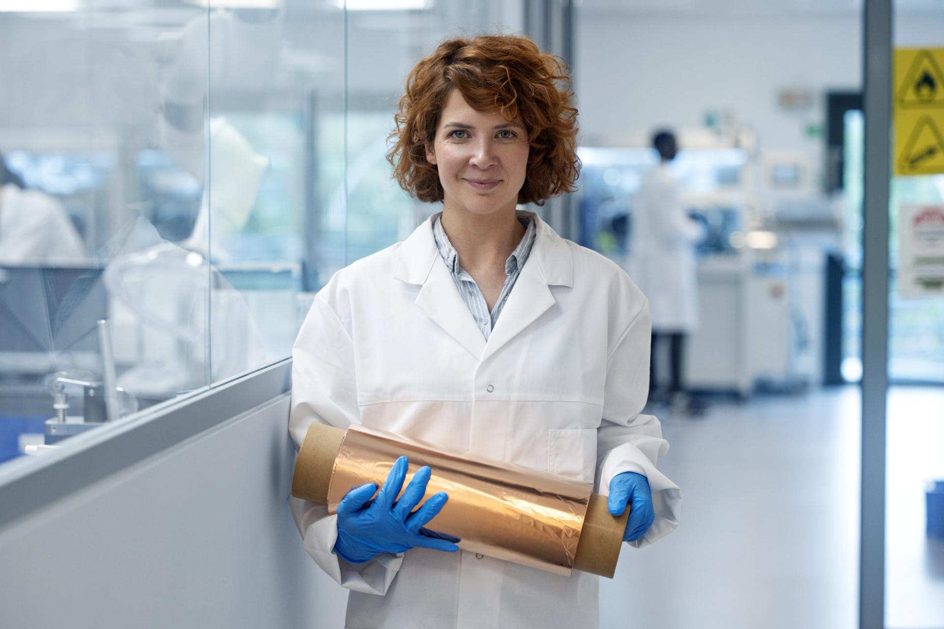 Image from battery production facility. Female research engineer with a copper roll for the anode.