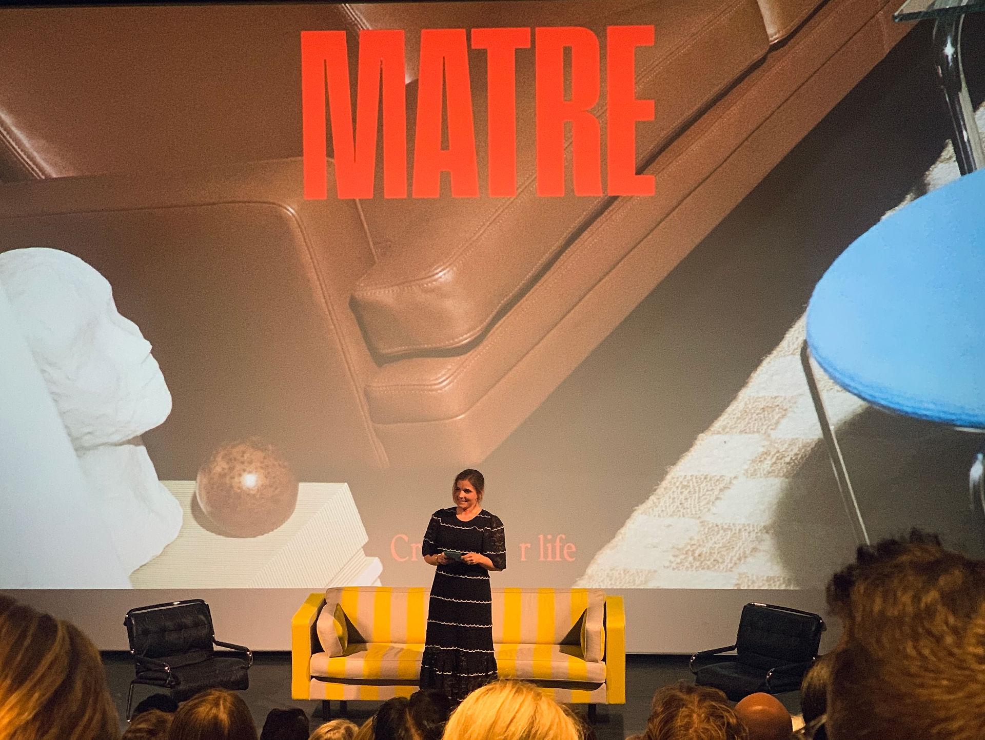 Woman in a black dress giving a presentation on a stage