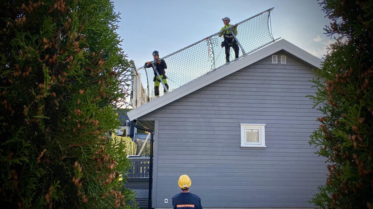 Workers standing on roof behind safety barrier