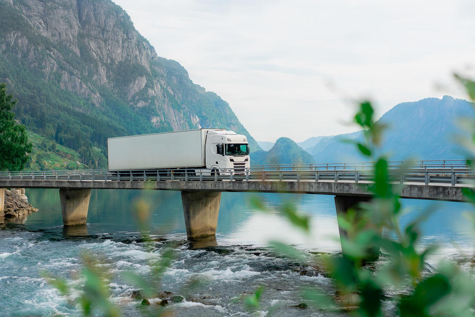 White truck driving on a bridge over a river