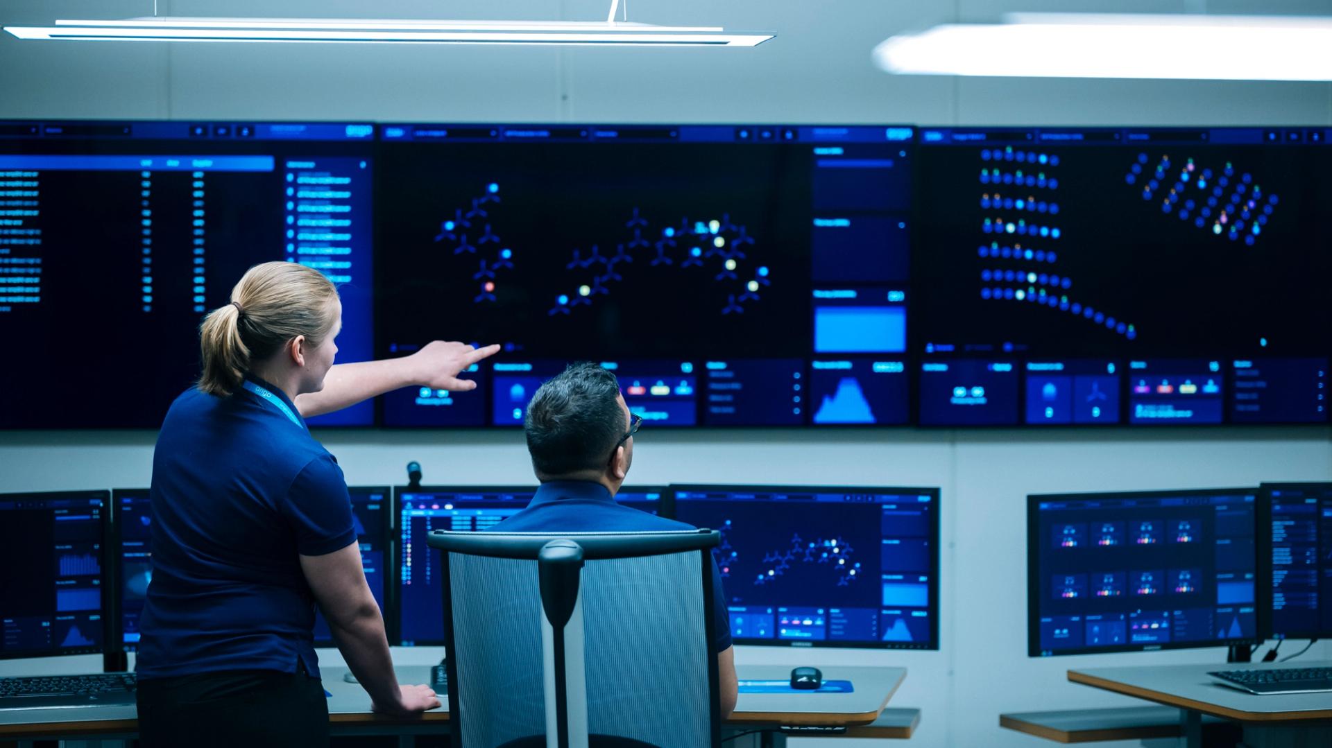 A woman and a man looking at insight on a big screen.