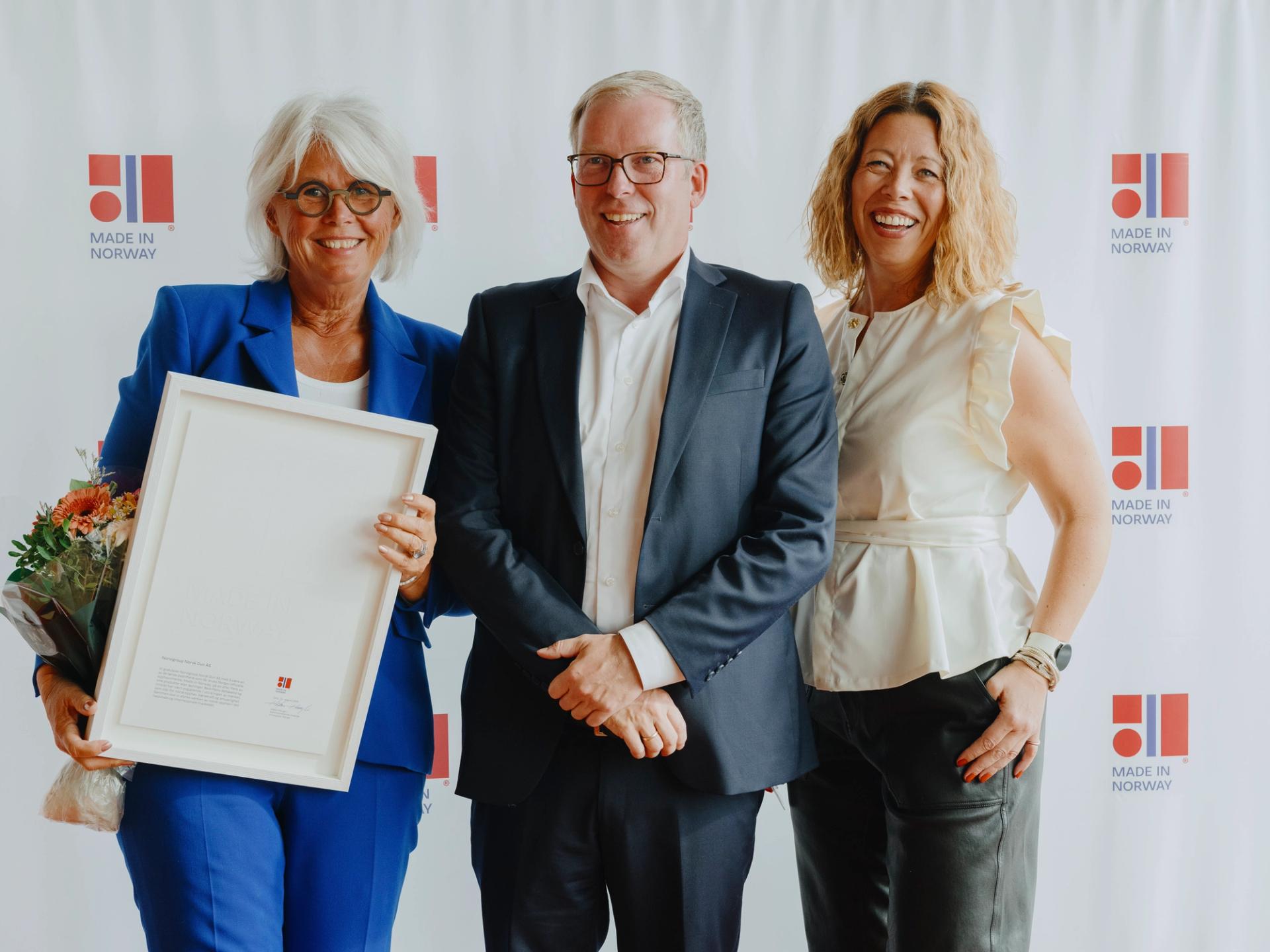 Picture showing three persons. Kari Setsaas CEO of Norvigroup Norsk Dun holding the Made in Norway certificate, Håkon Haugli,  CEO of Innovation Norway and Therese Haltuff, Head of International Business of Norvigroup Norsk Dun.