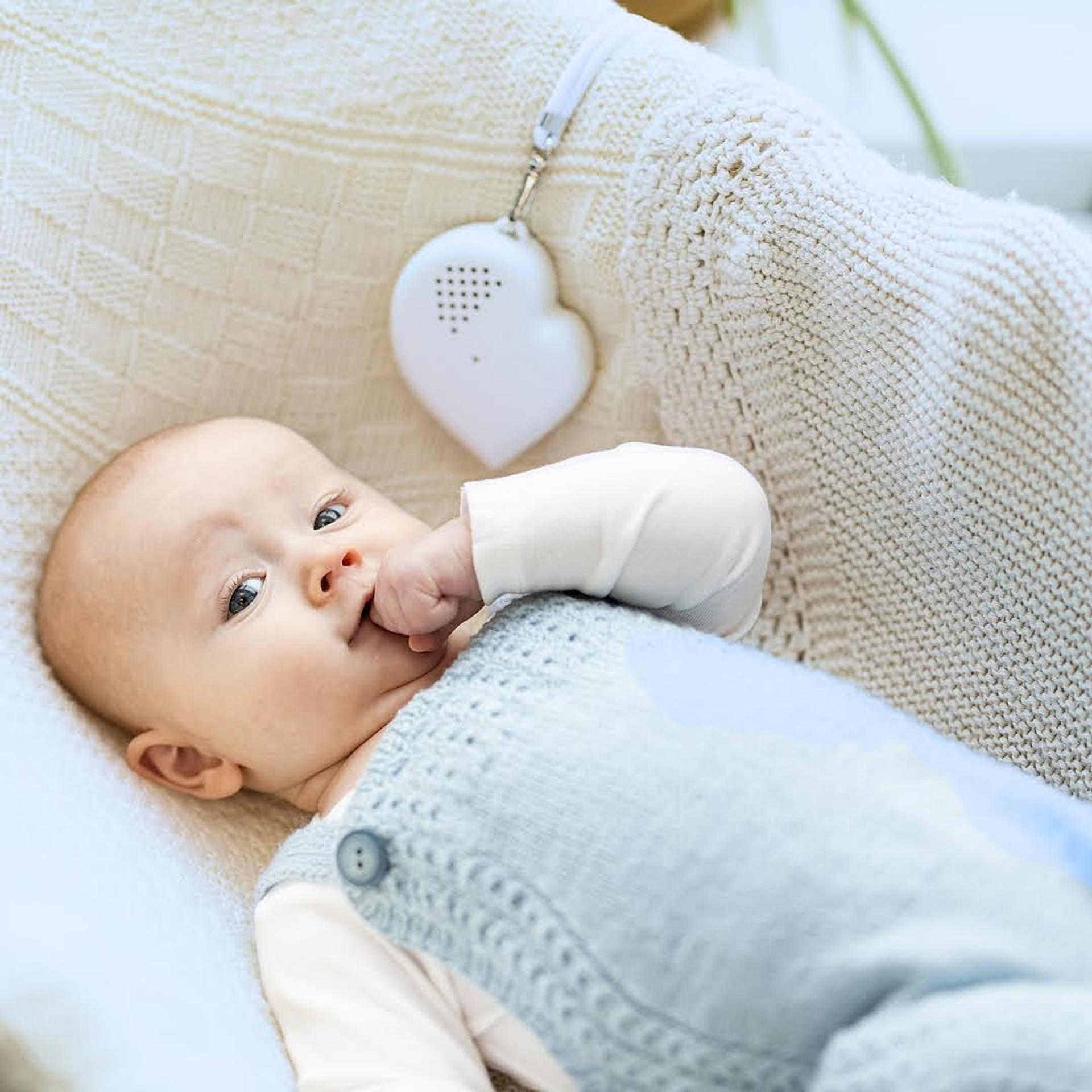 A baby laying in a crib with a colic button.