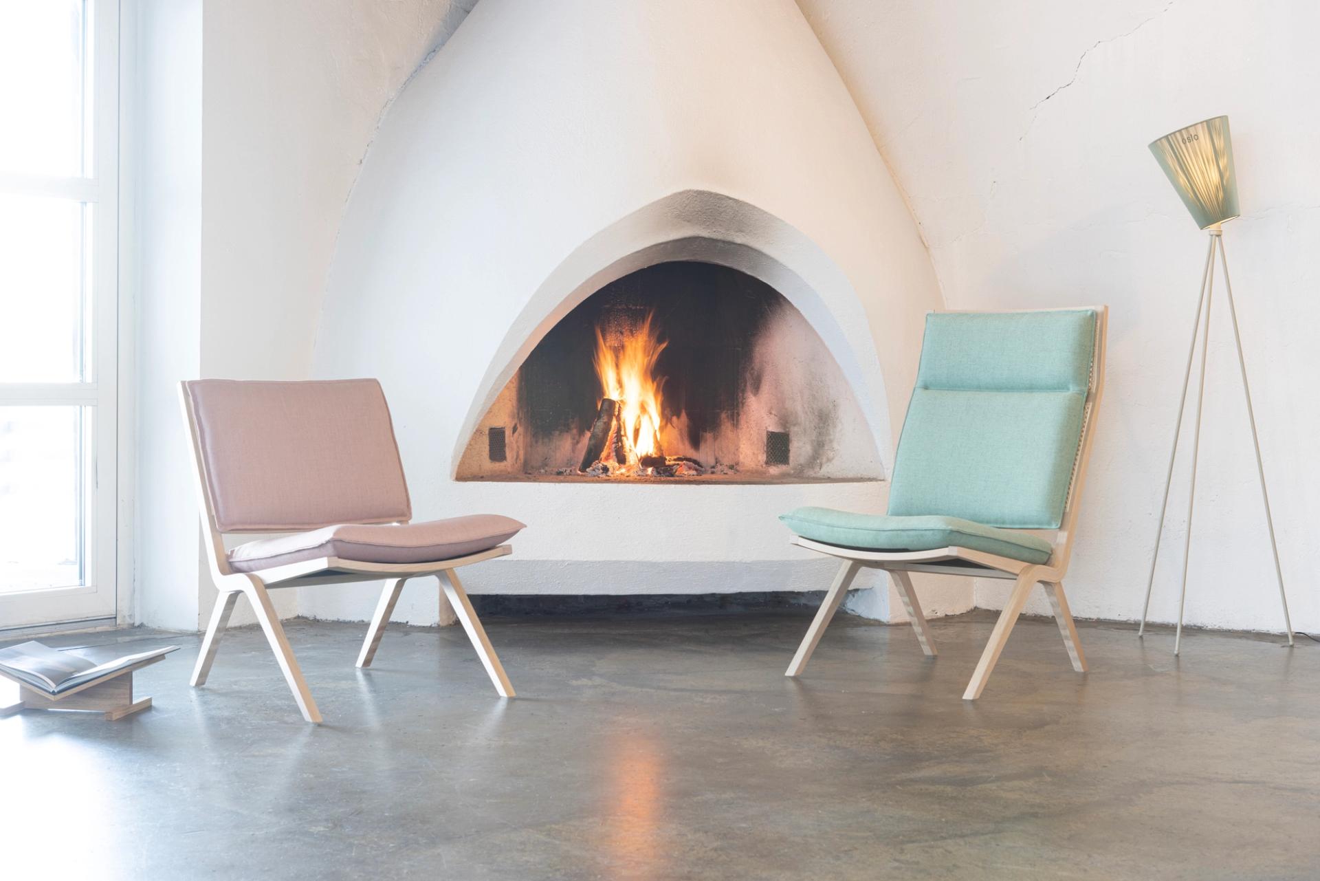 High-backed mint green easy chair and low-backed pale pink easy chair in front of a white fireplace