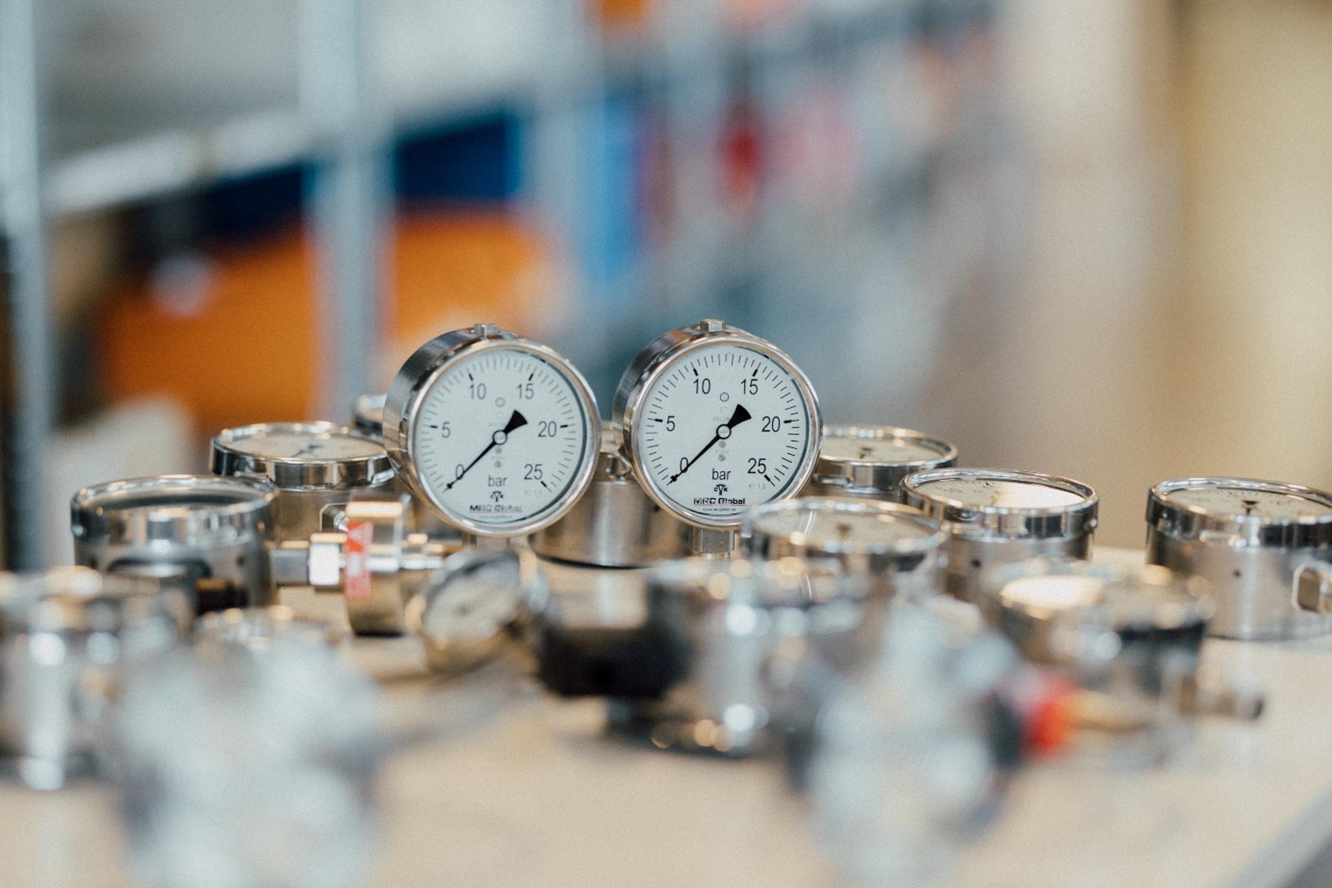 Pressure gauges on a table, with more gauges and fittings in the background