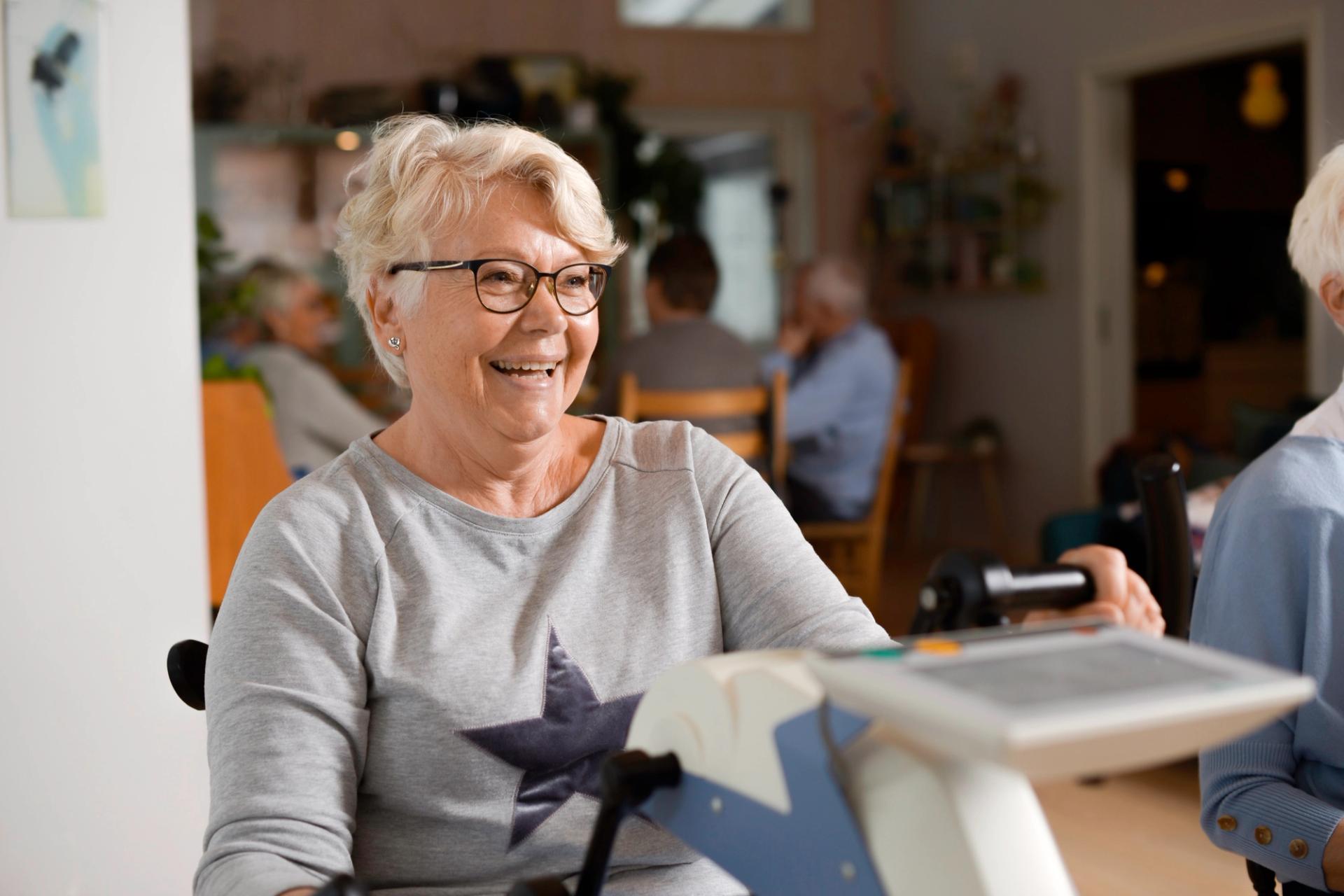 Smiling grey haired woman on a stationary bicycle