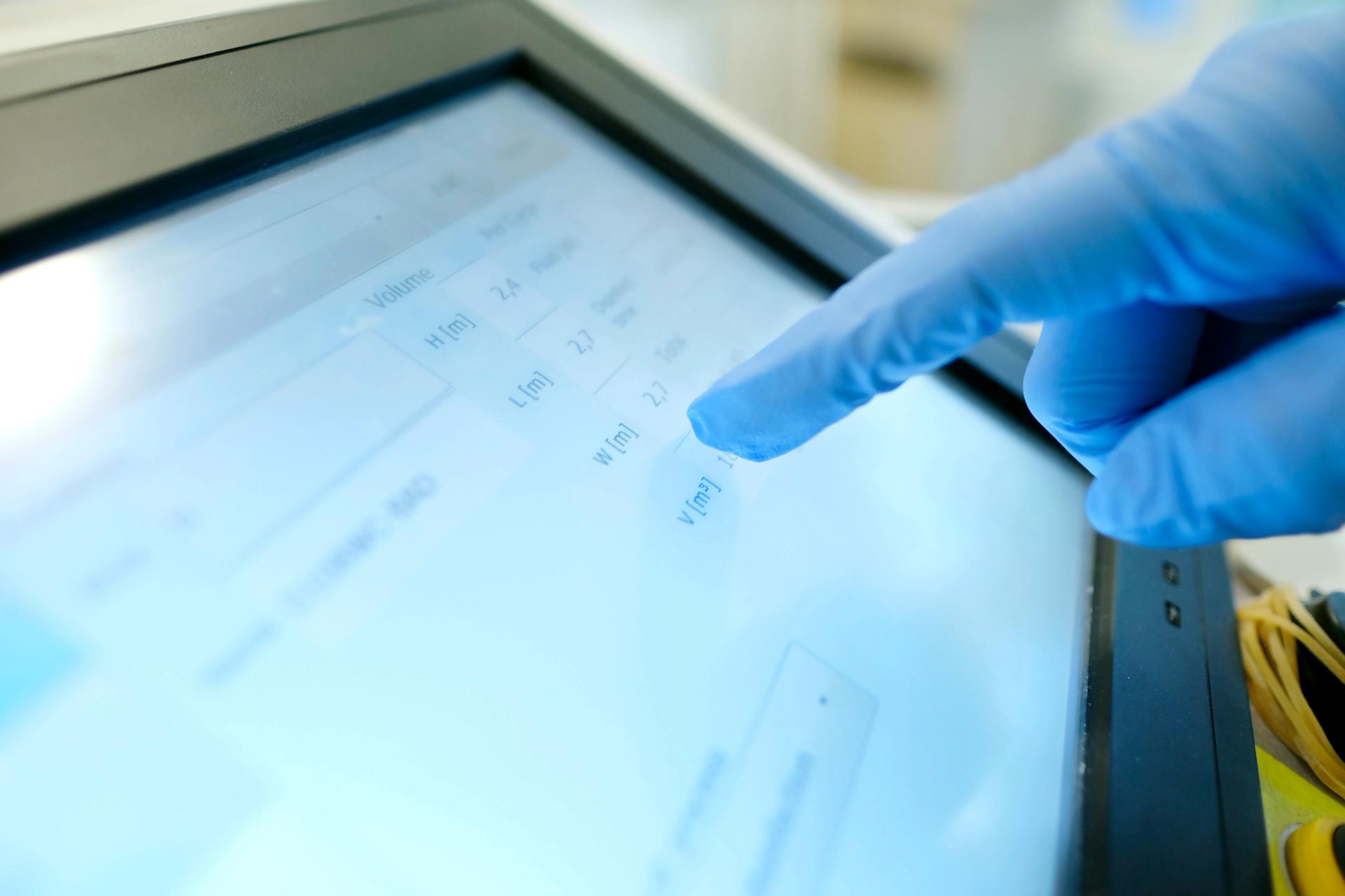 Blue gloved hand touching a screen