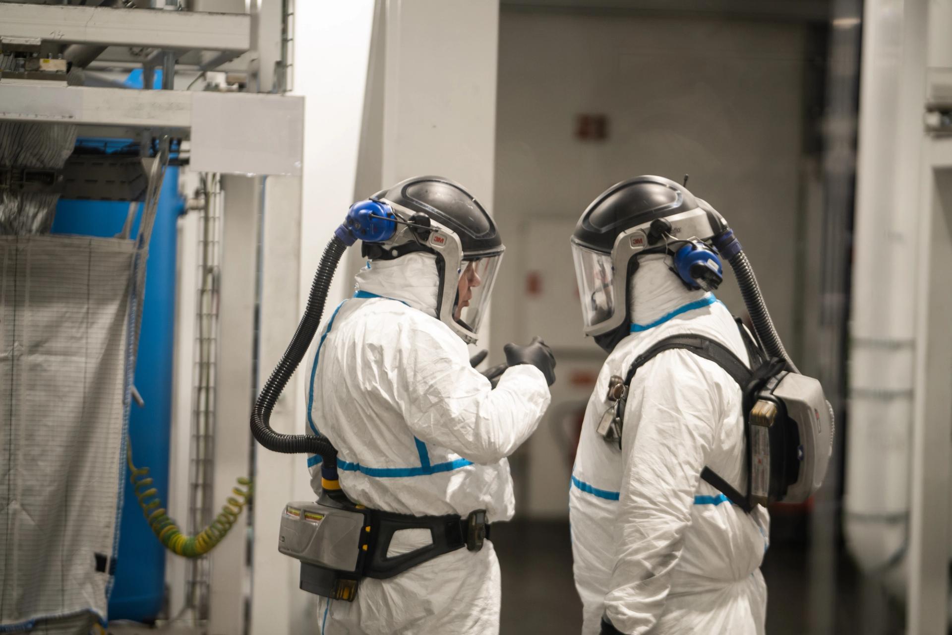 Workers in protective gear at a battery recycling plant