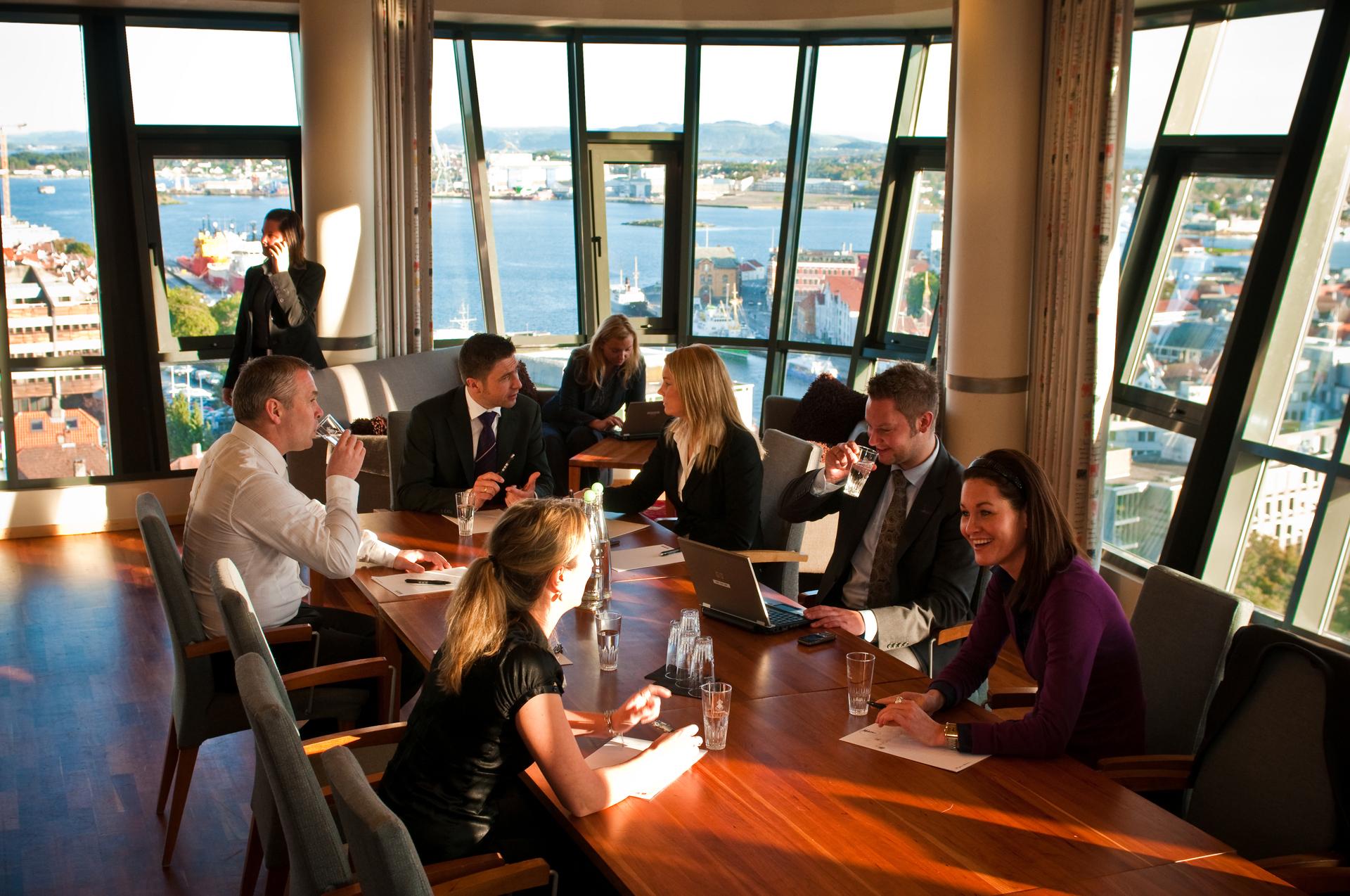 Board meeting with people around a teak table against a sea view of Stavanger