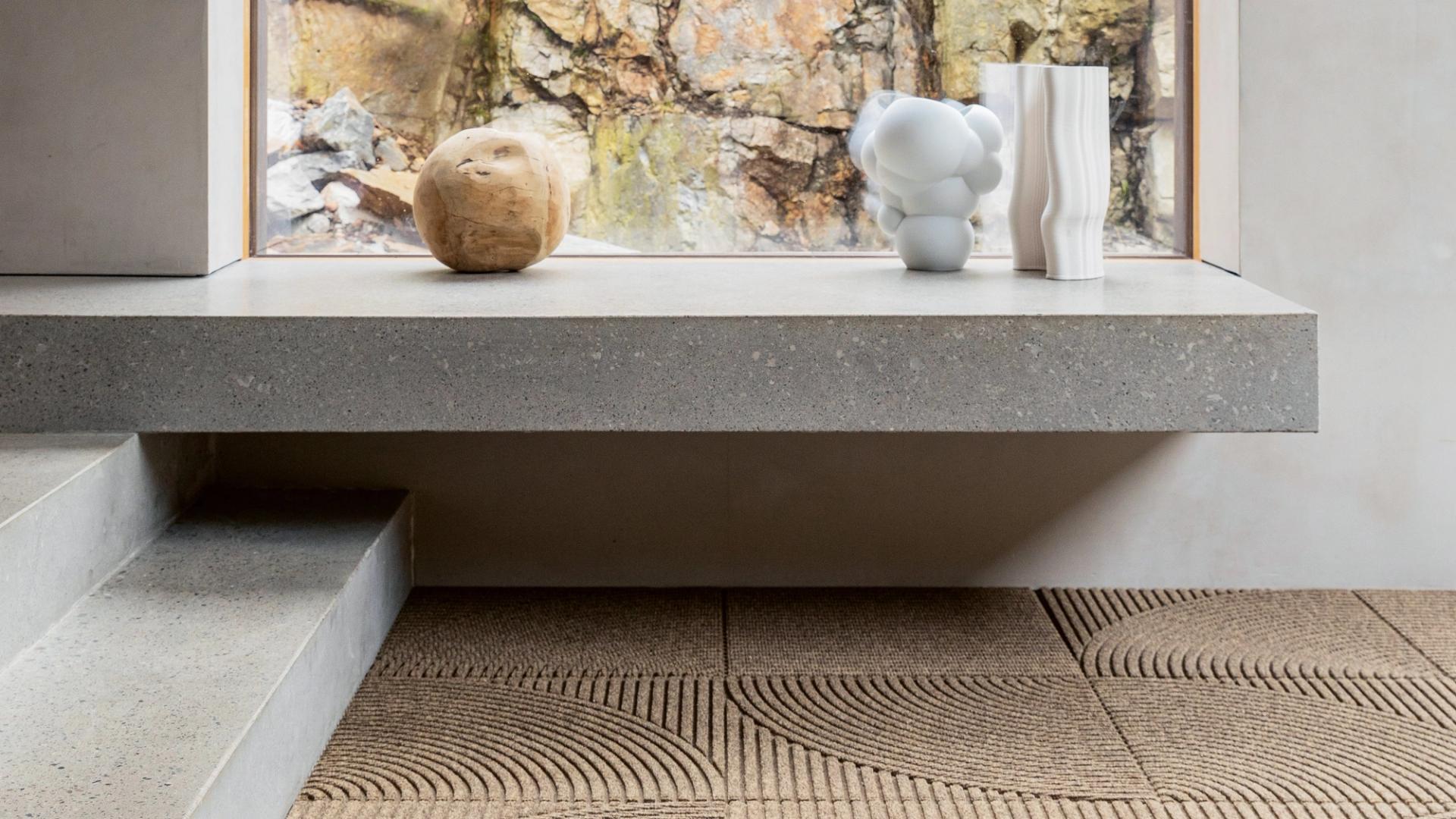 Grey marble shelf with abstract objects above a swirly brown carpet