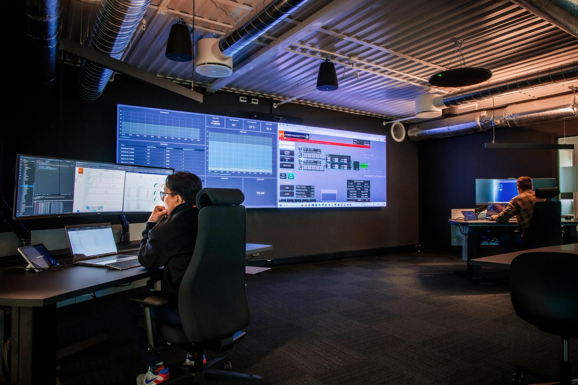 Woman in a control room in front of a wall sized screen