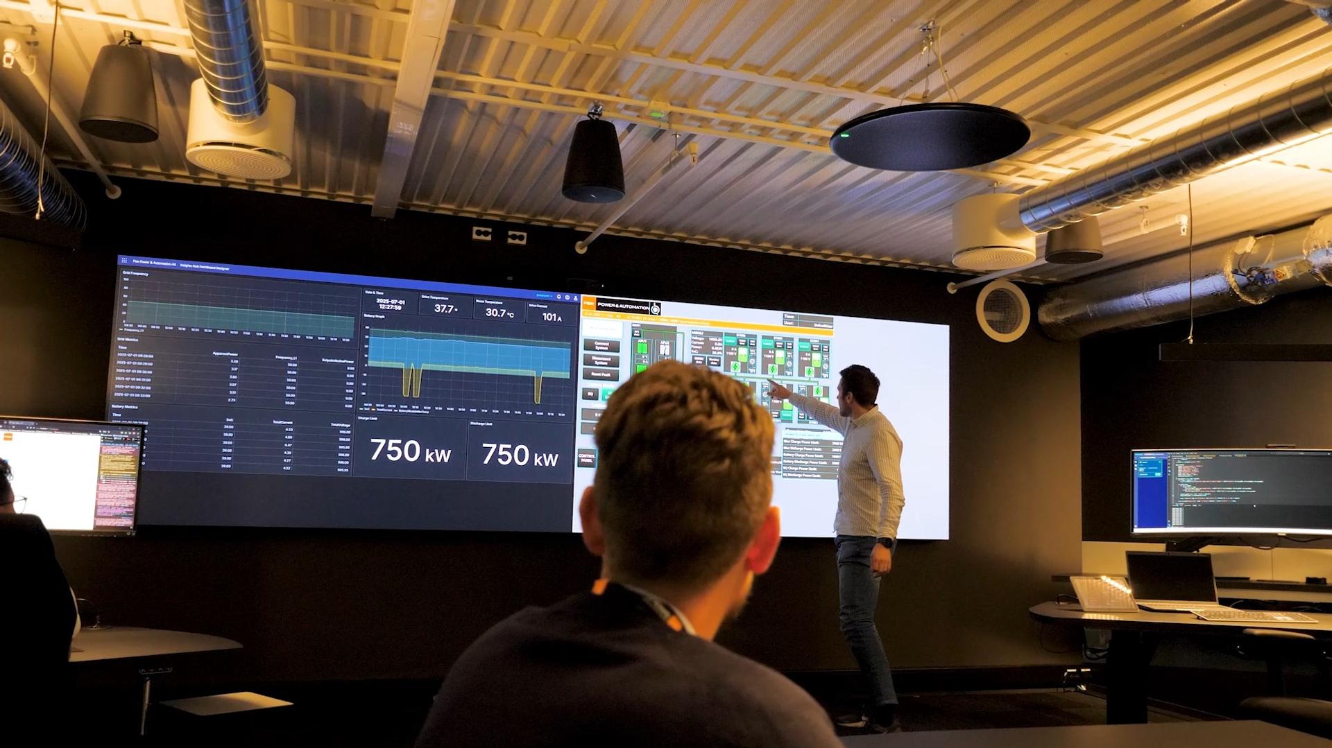 Man in a control room in front of a wall sized screen