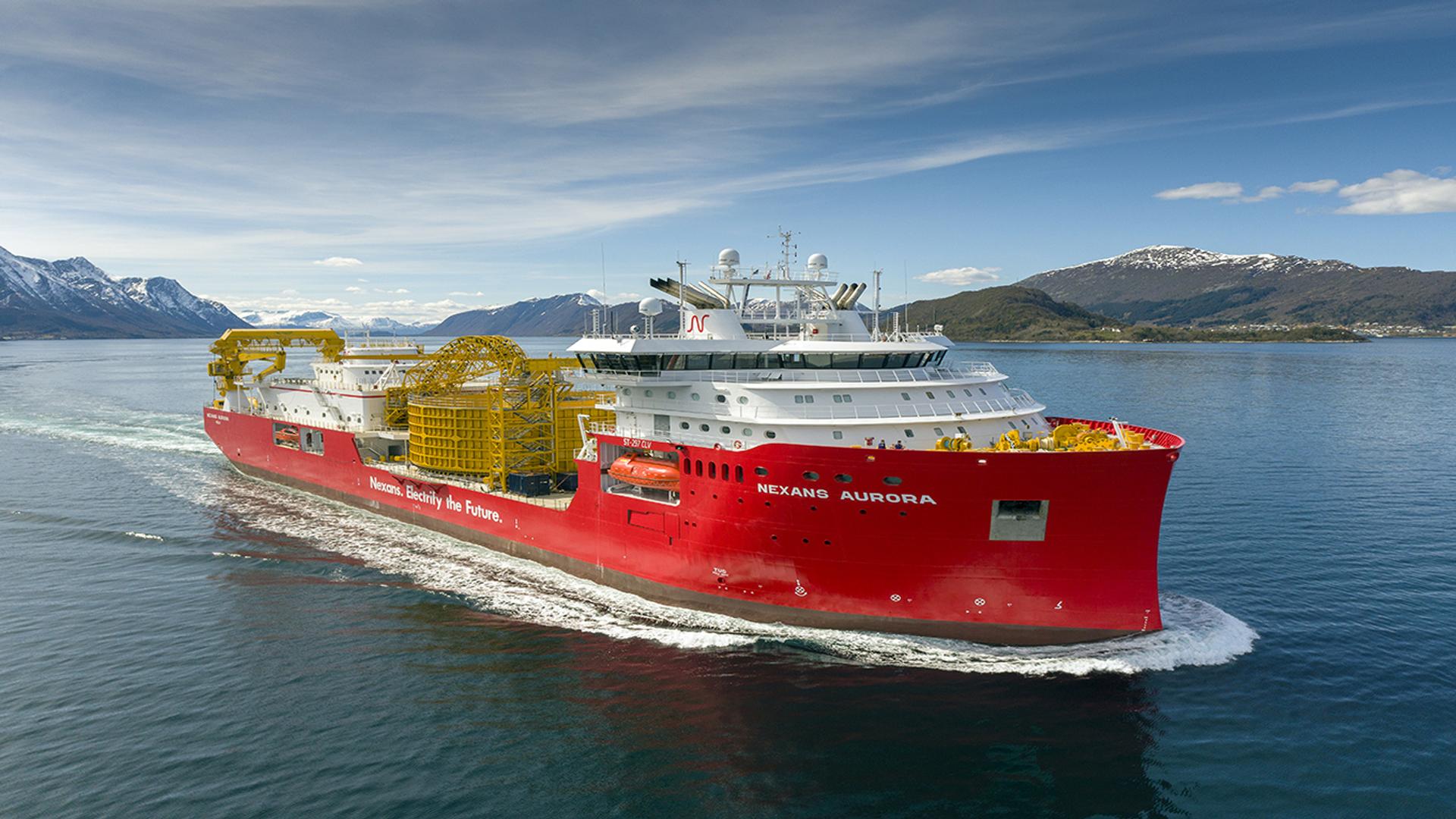 Red cable laying vessel sailing in a fjord