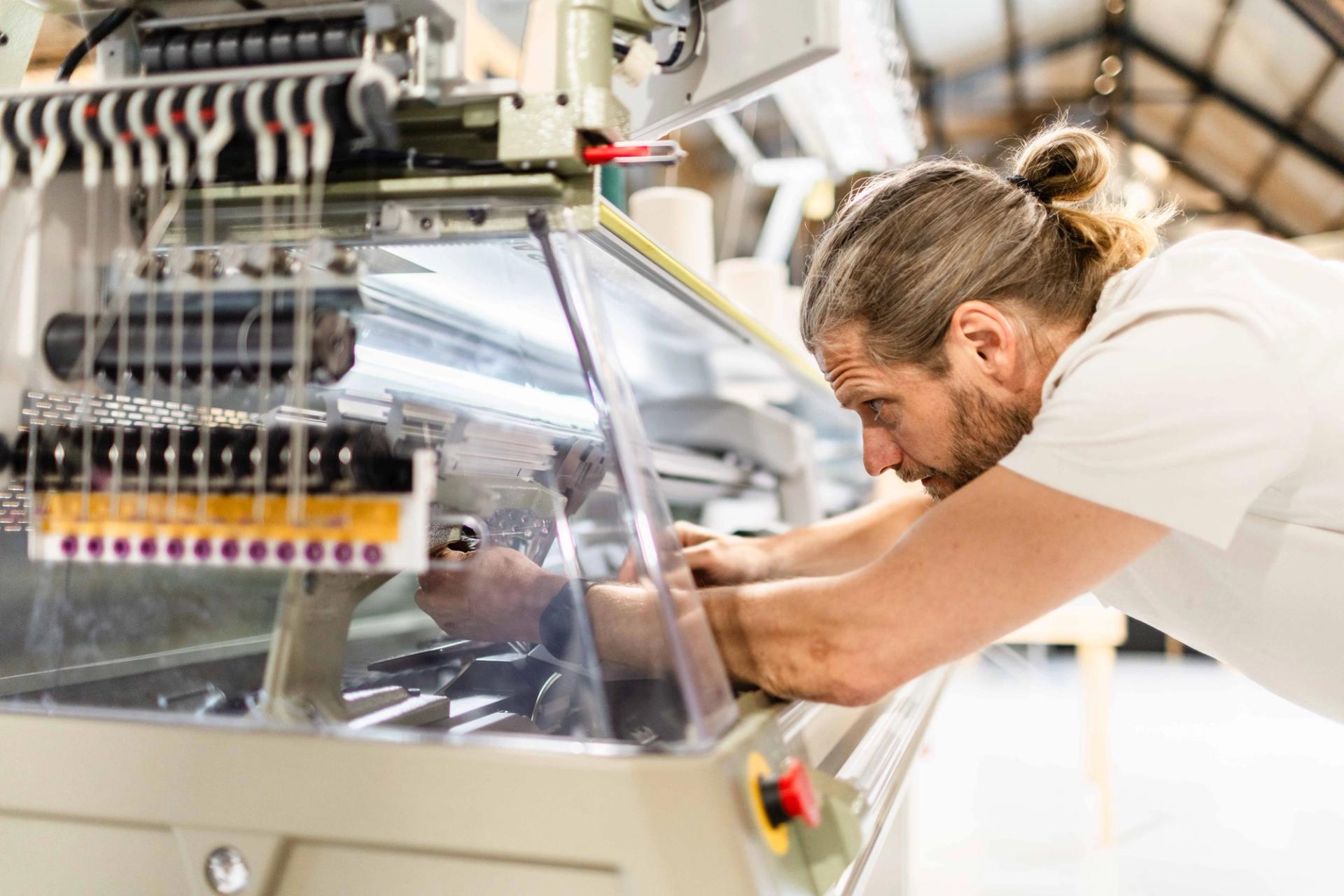 A man operating a textile machine in a fabric.