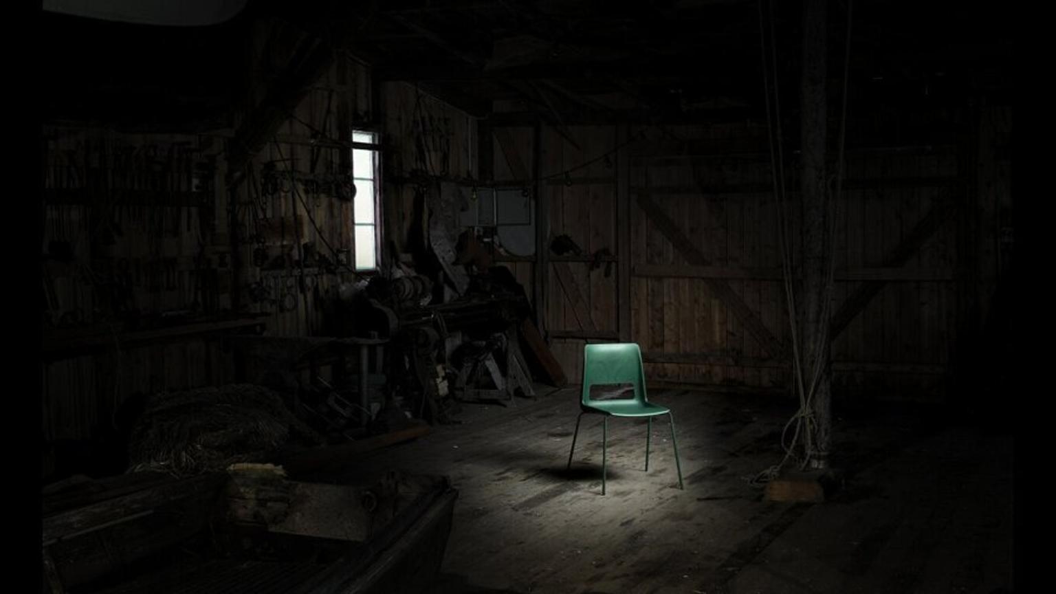 Green chair inside a wood barn