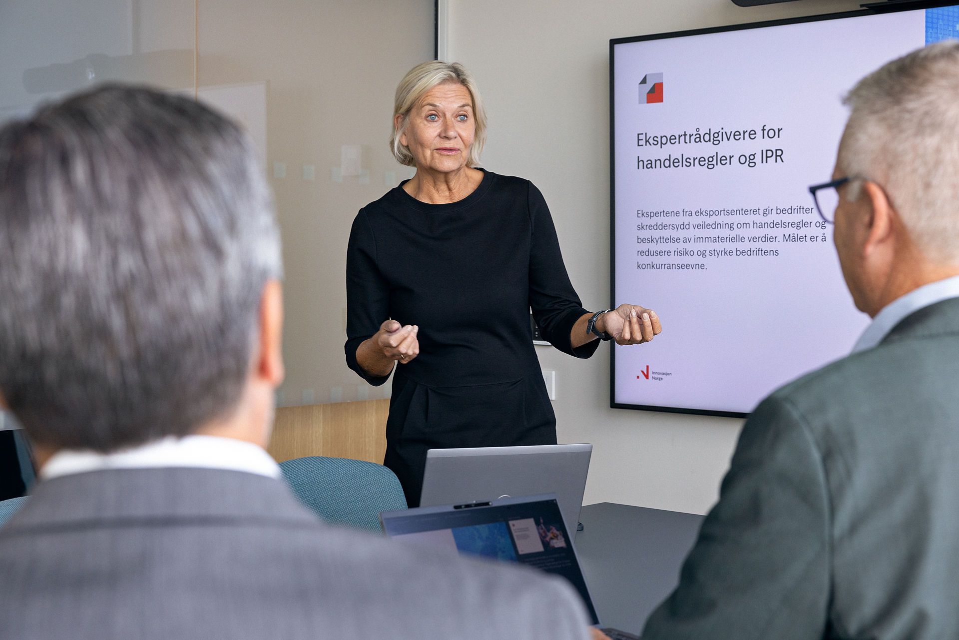 Kvinne presenterer ekspertrådgivere for handelsregler og IPR for to menn