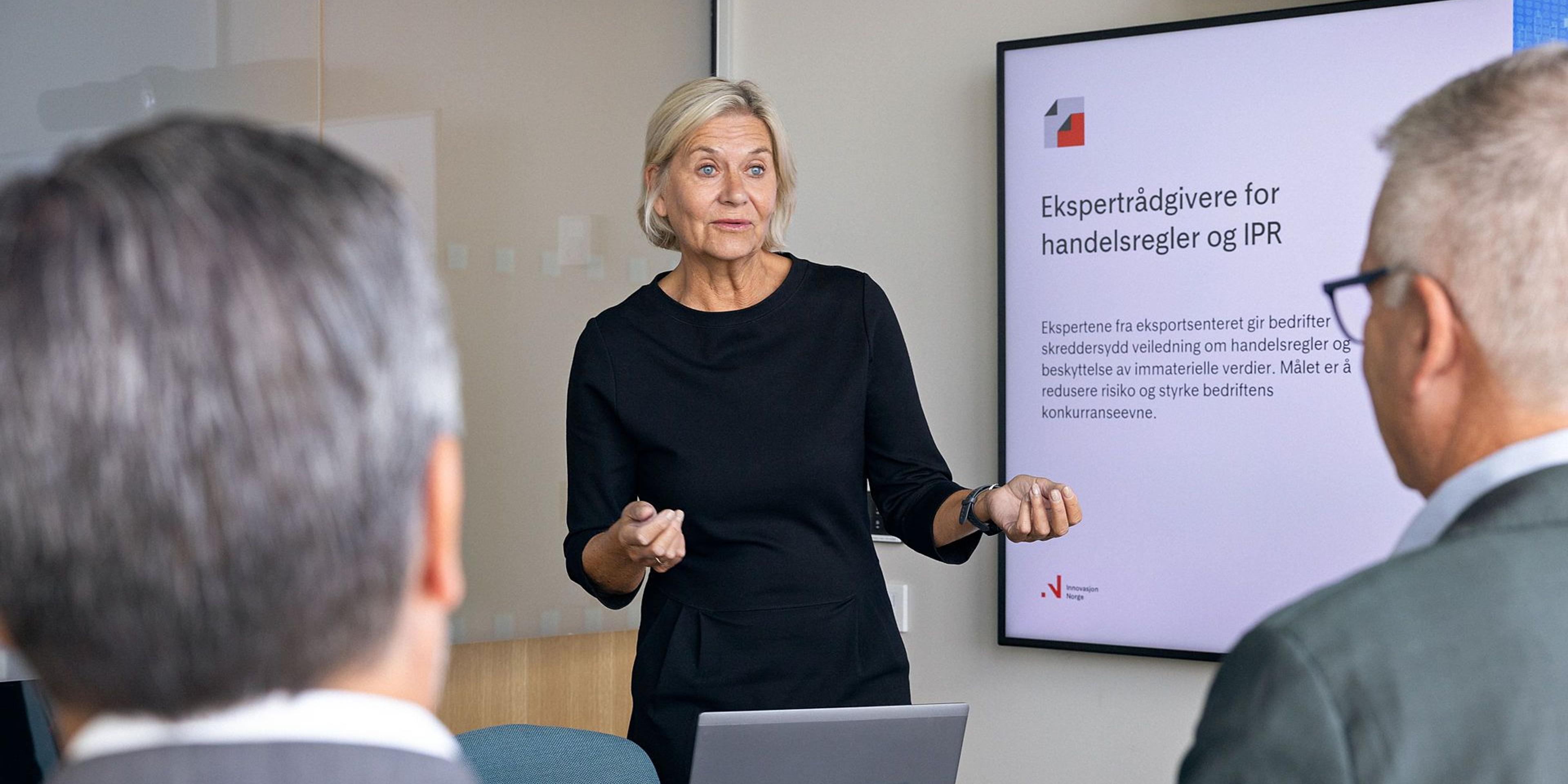 Kvinne presenterer ekspertrådgivere for handelsregler og IPR for to menn