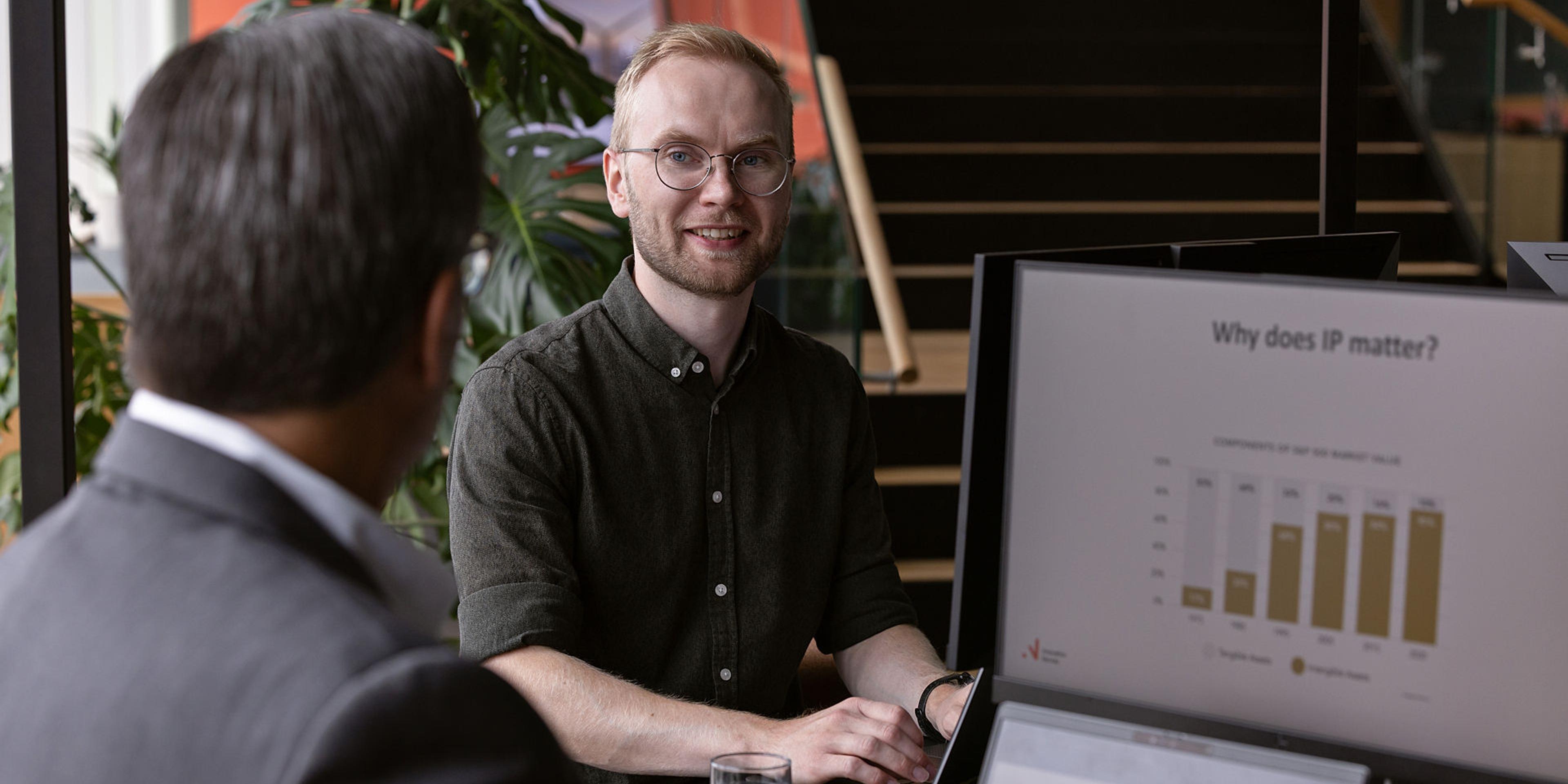 En mann foran en pc-skjerm gir rådgivning til en annen mann om IP