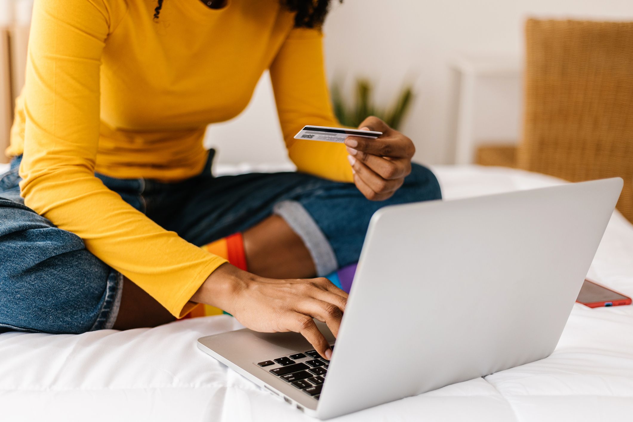 Nærbilde av dames hånd som holder et kredittkort for å utføre kjøp på laptop. E-handel og shopping online som konsept.