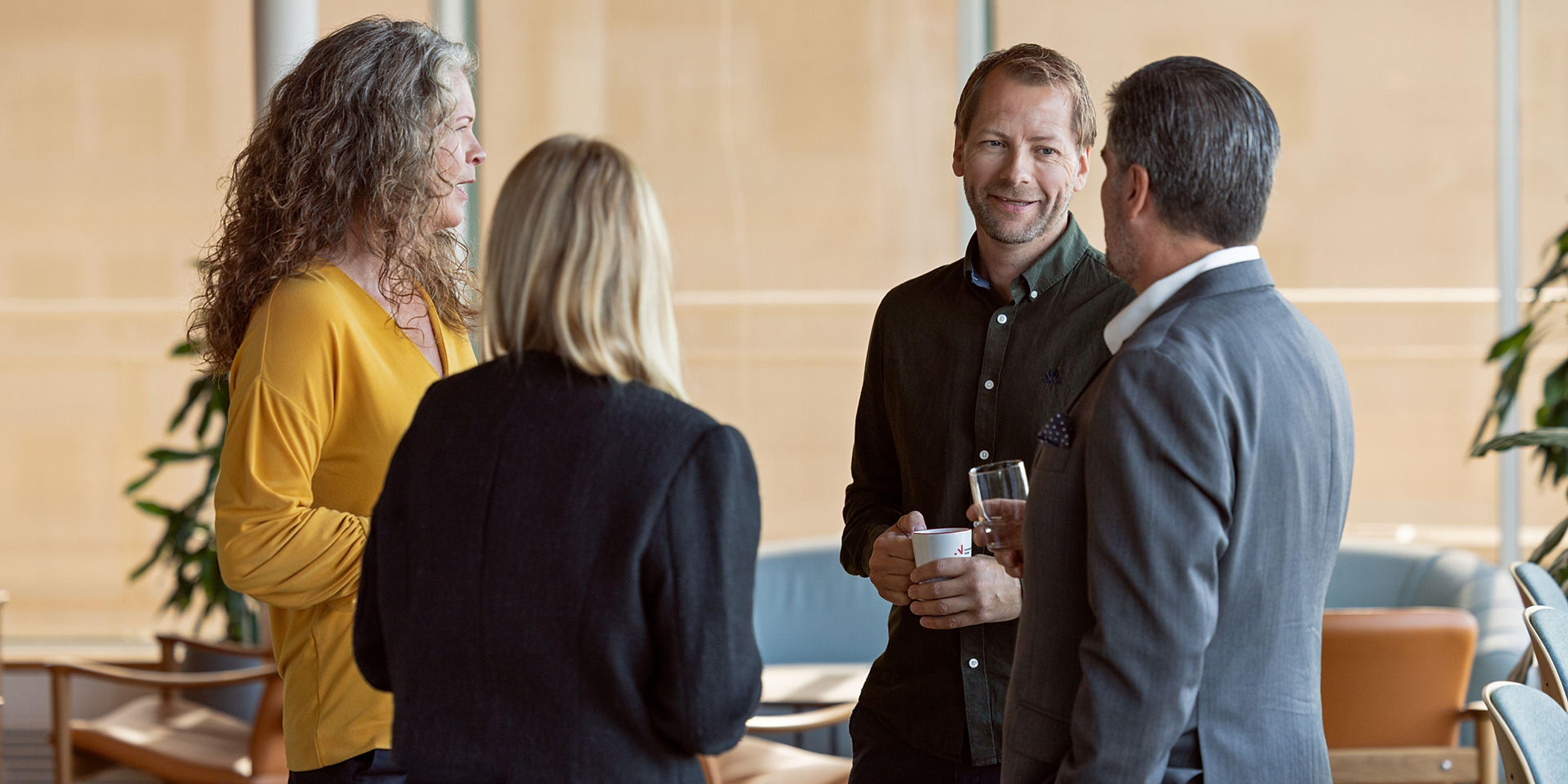 En gruppe på fire personer står og snakker sammen