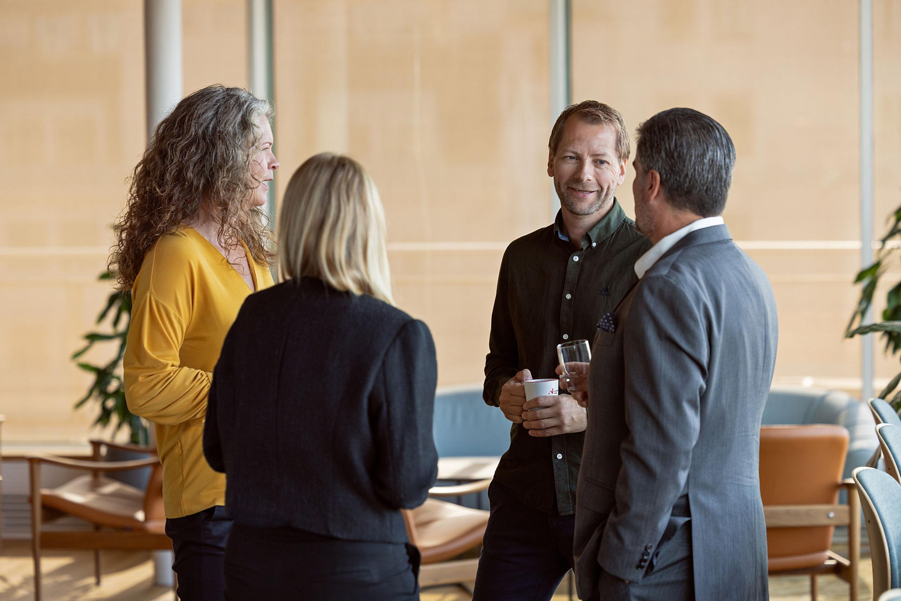 En gruppe på fire personer står og snakker sammen