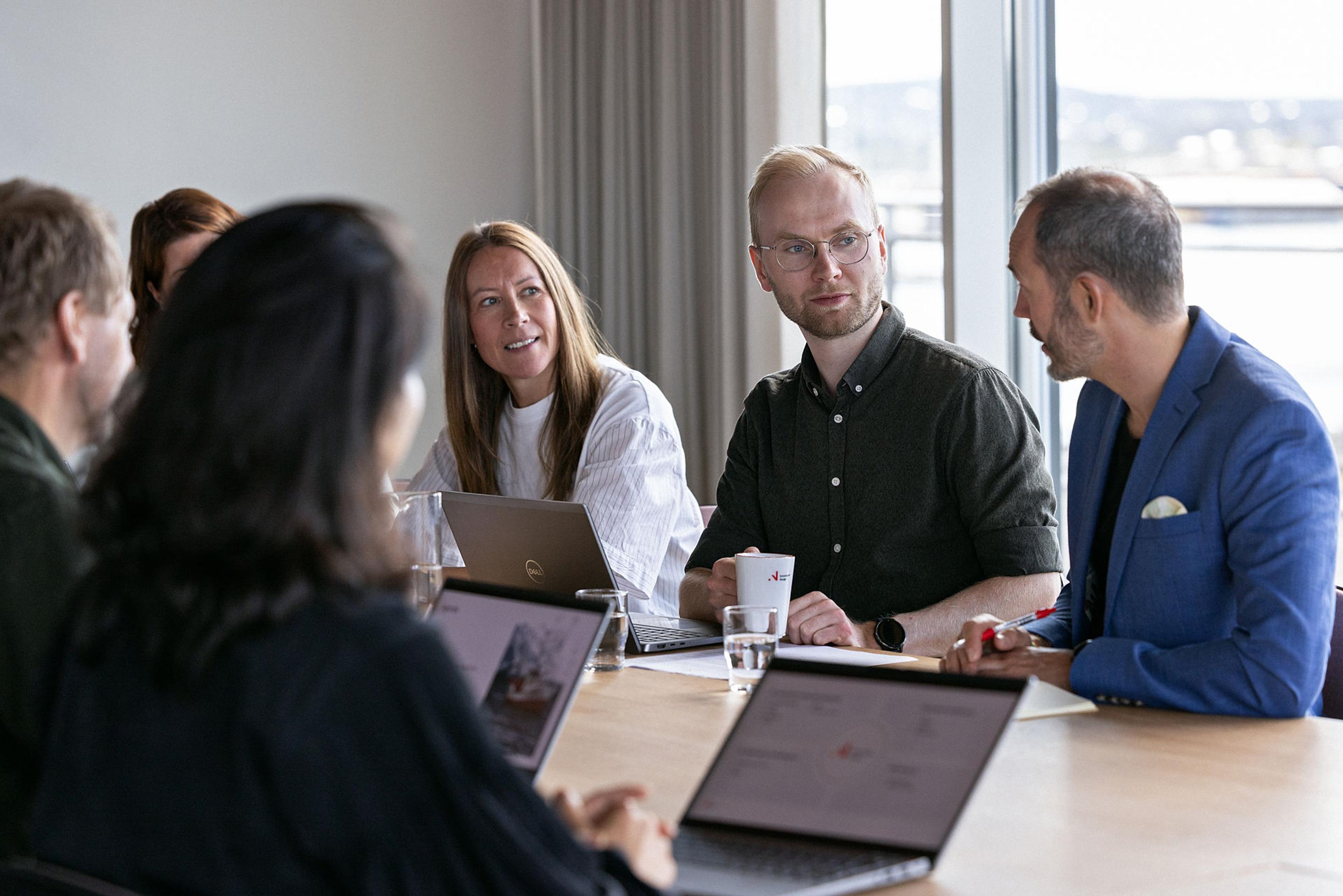 En gruppe mennesker snakker sammen rundt et møtebord