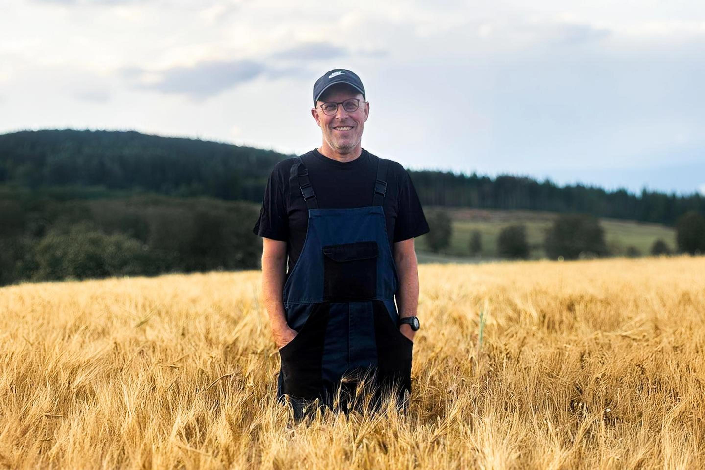 Glad bonde stående i åker.