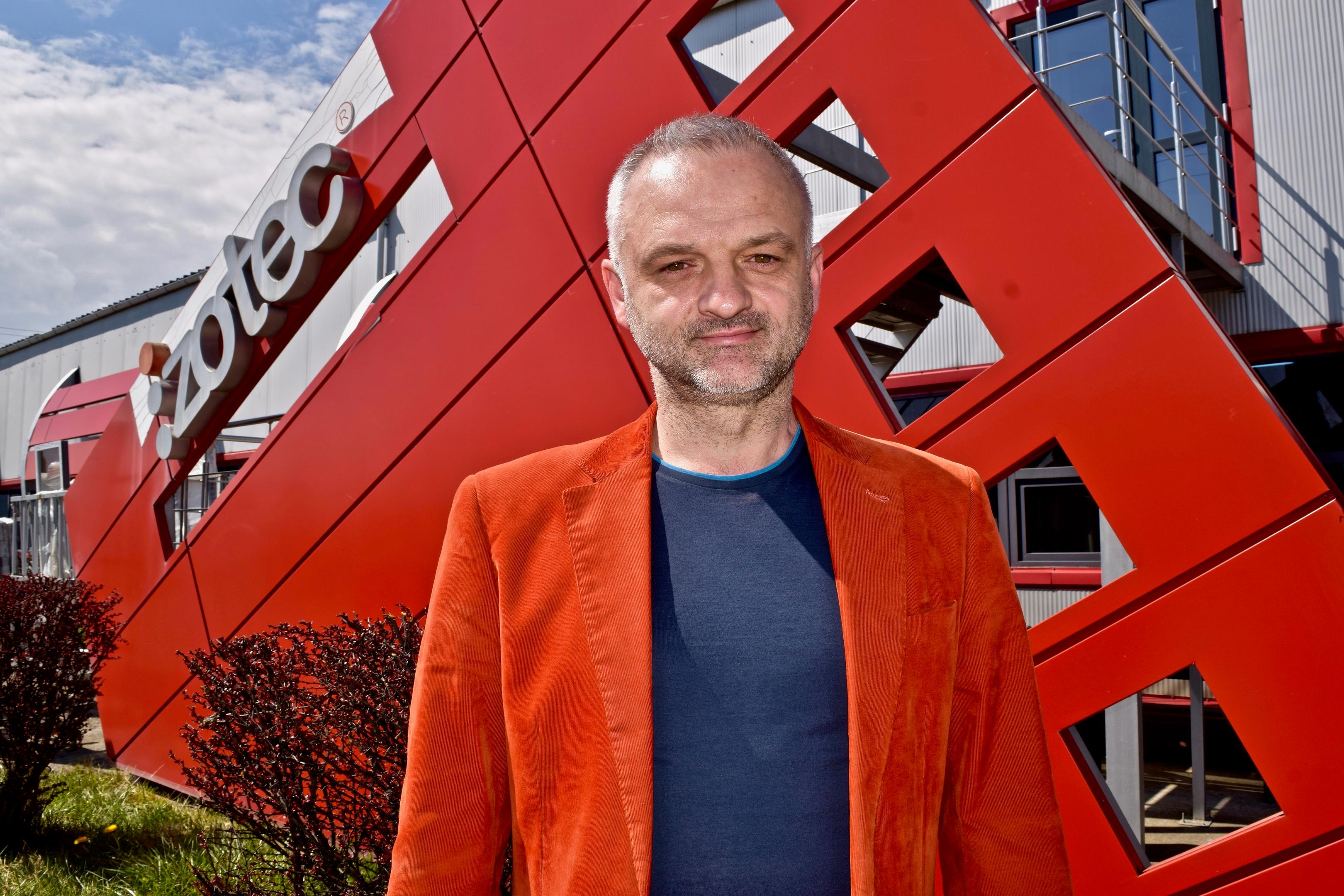 A picture of the CEO in red, in front of the red building Izotec
