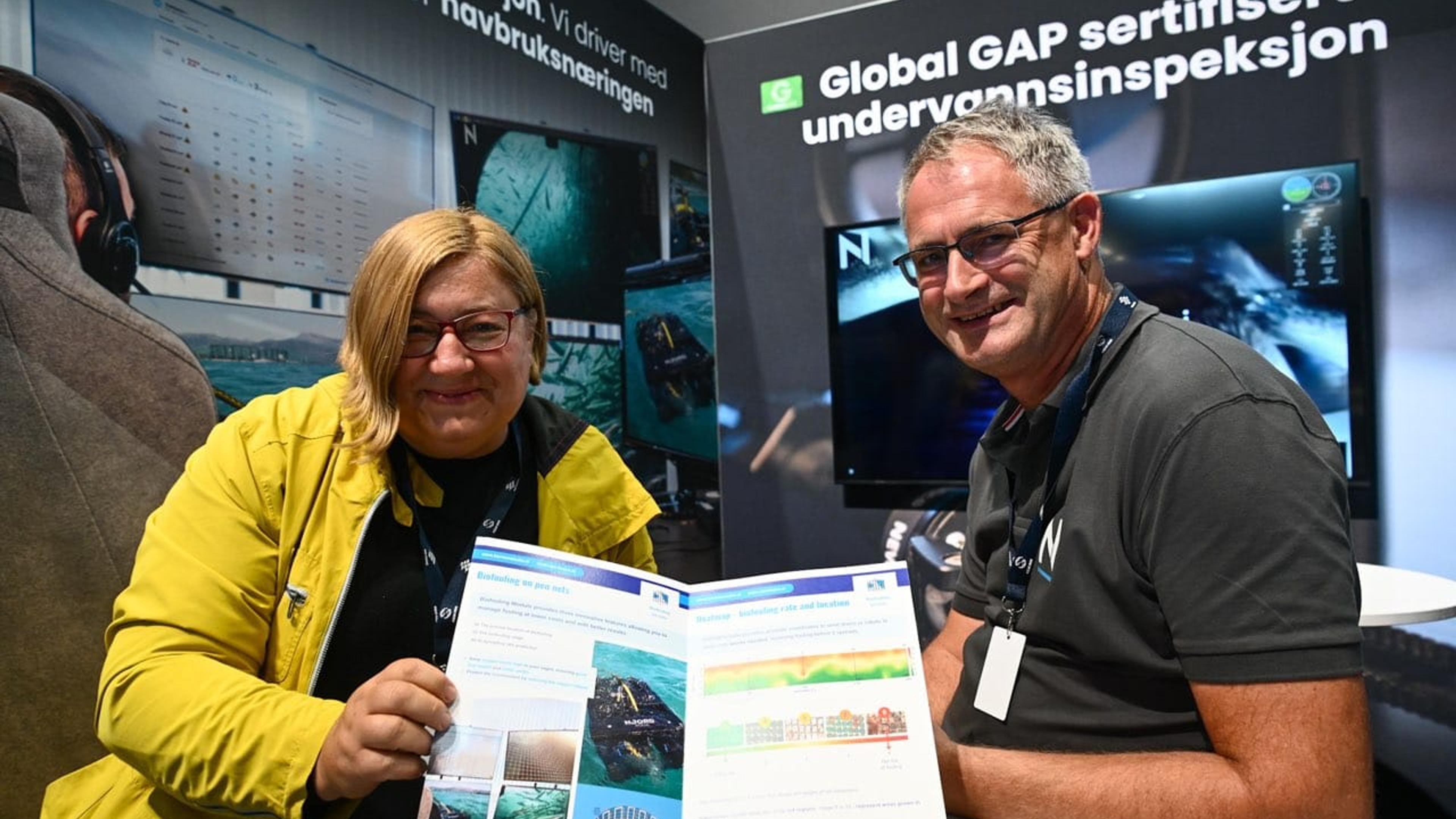 Two people smiling with a leaflet of their common project