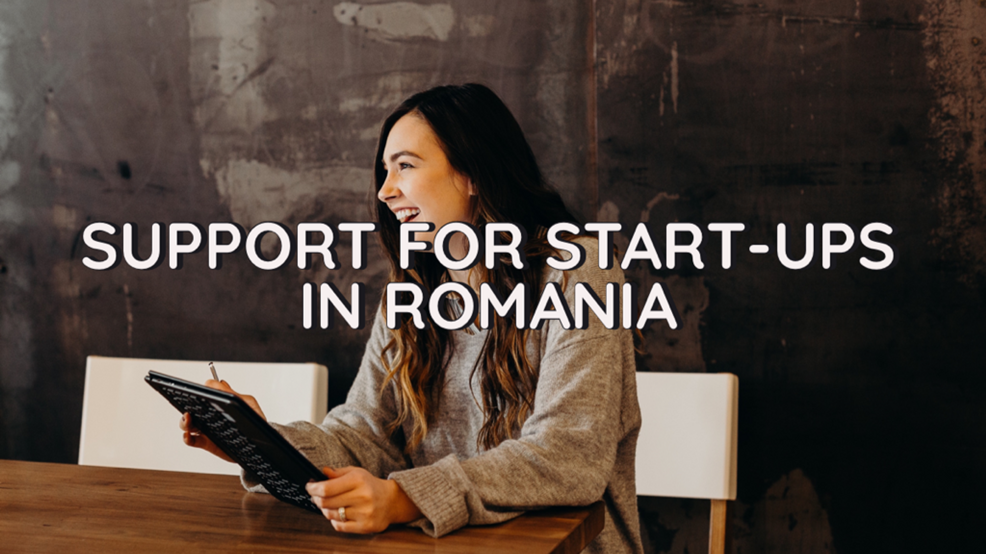 Woman sitting by a table with the words 'support for startups in Romania' over the picture