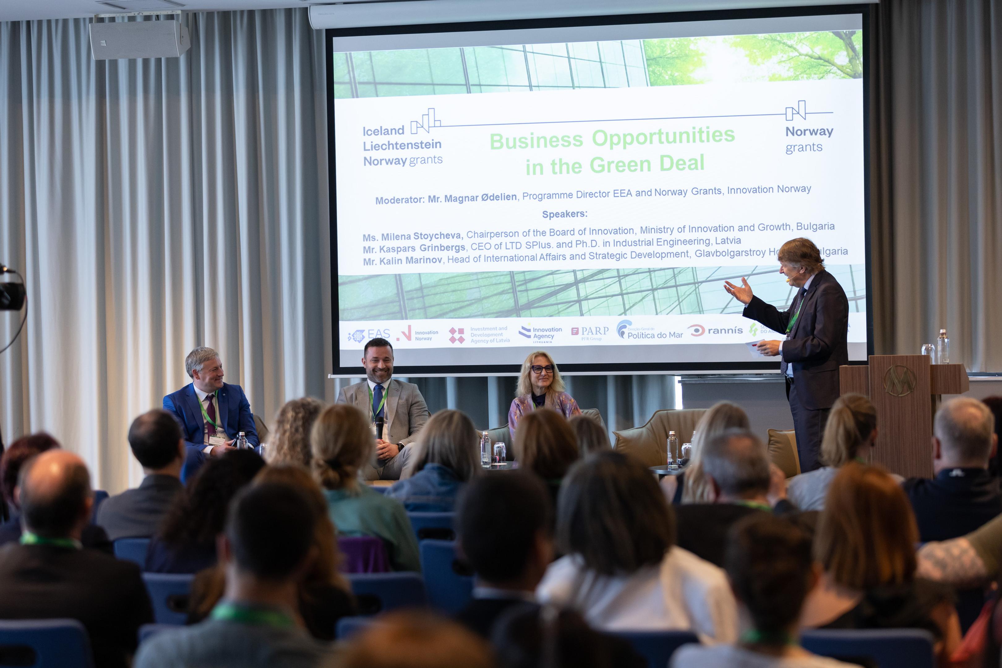 The panel from the plenary session. Panellists smiling and moderator gesticulating