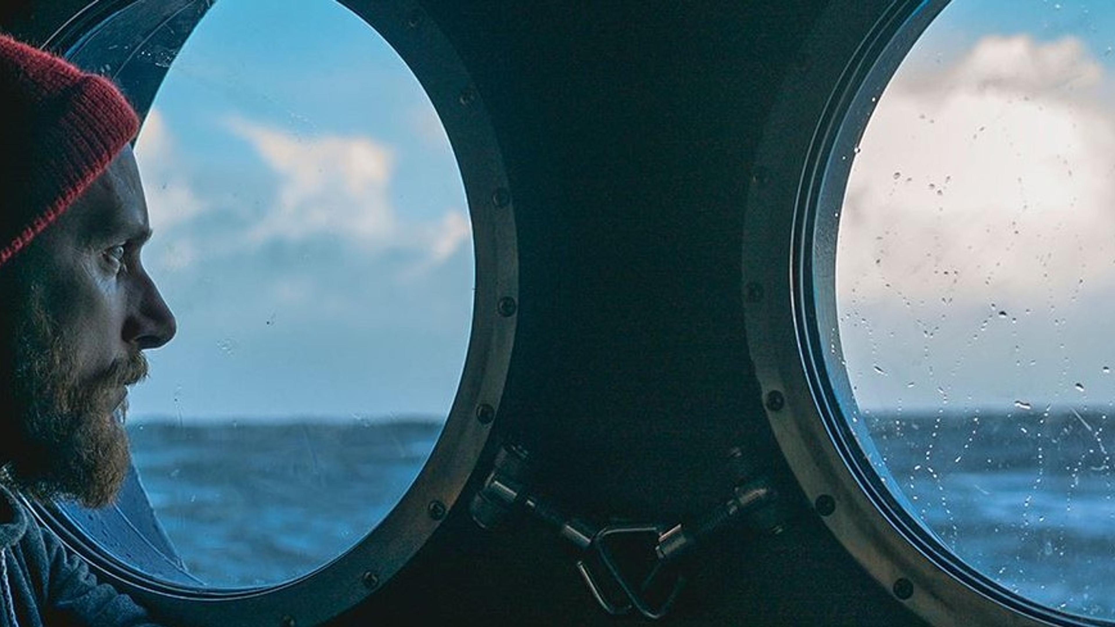 Mann som ser ut over havet gjennom et koøye