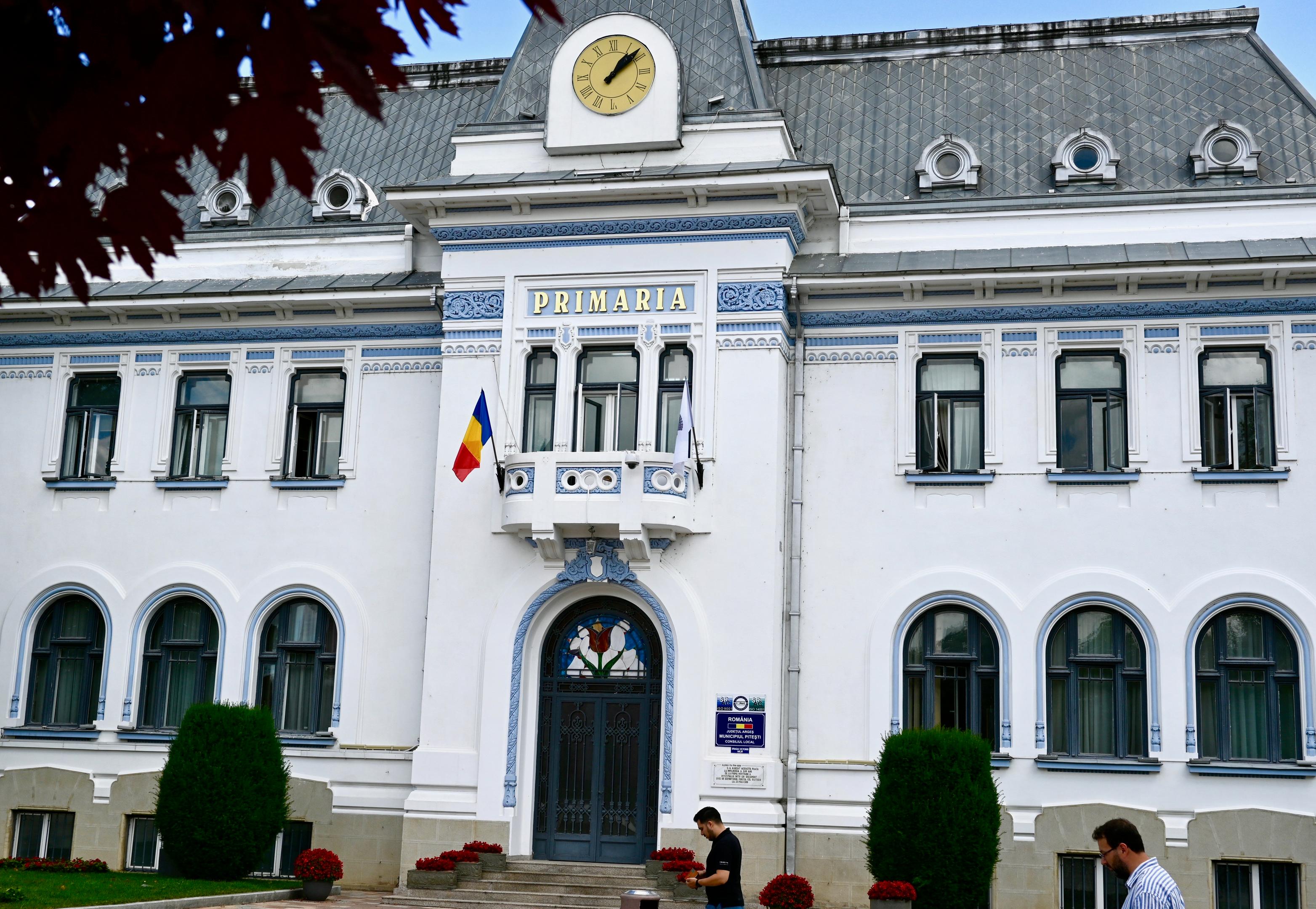The historical building of the Town Hall in Pitesti. A white old building with the romanian flag and blue details
