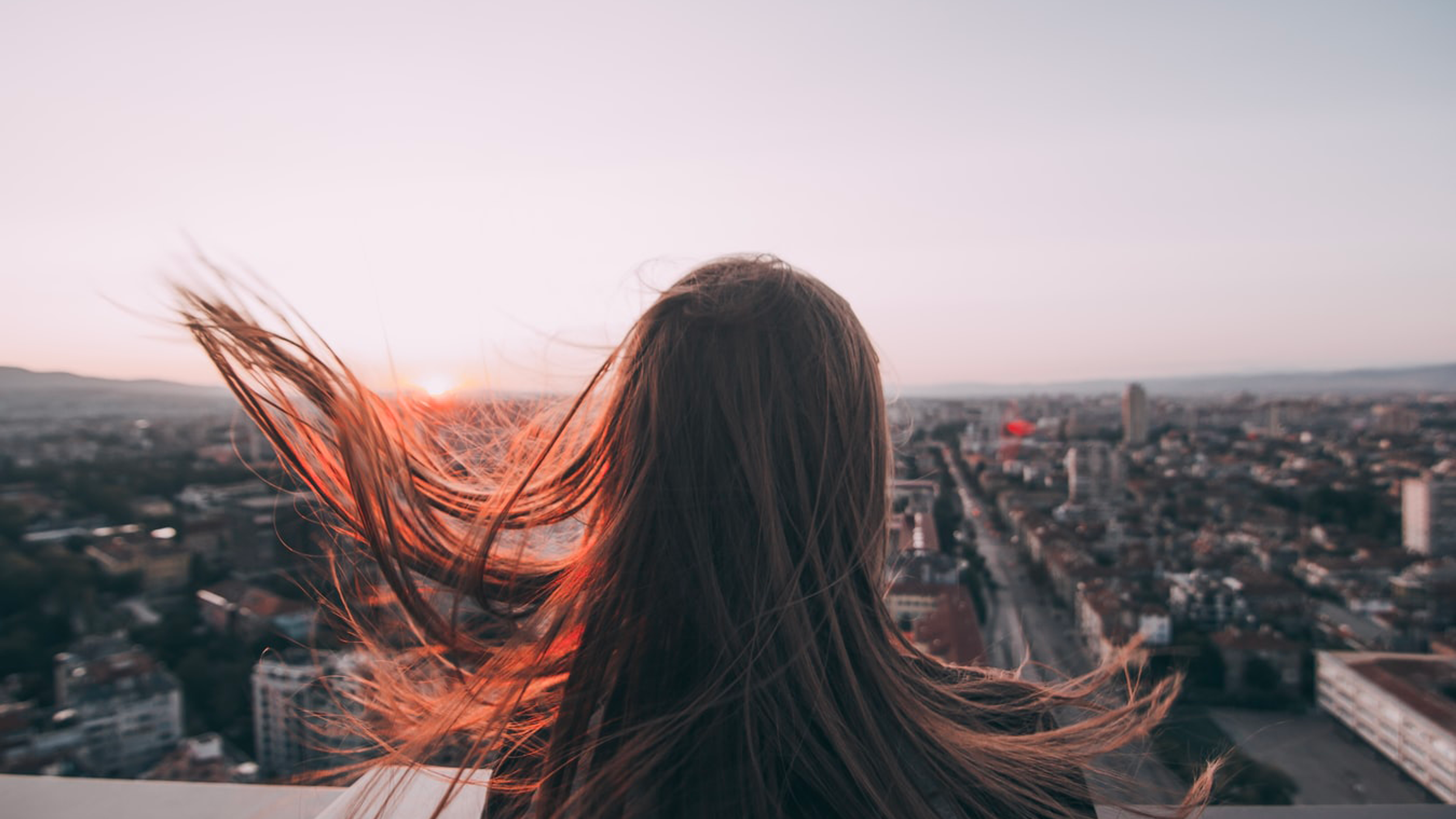 Person with long hair in the wind looking over the city