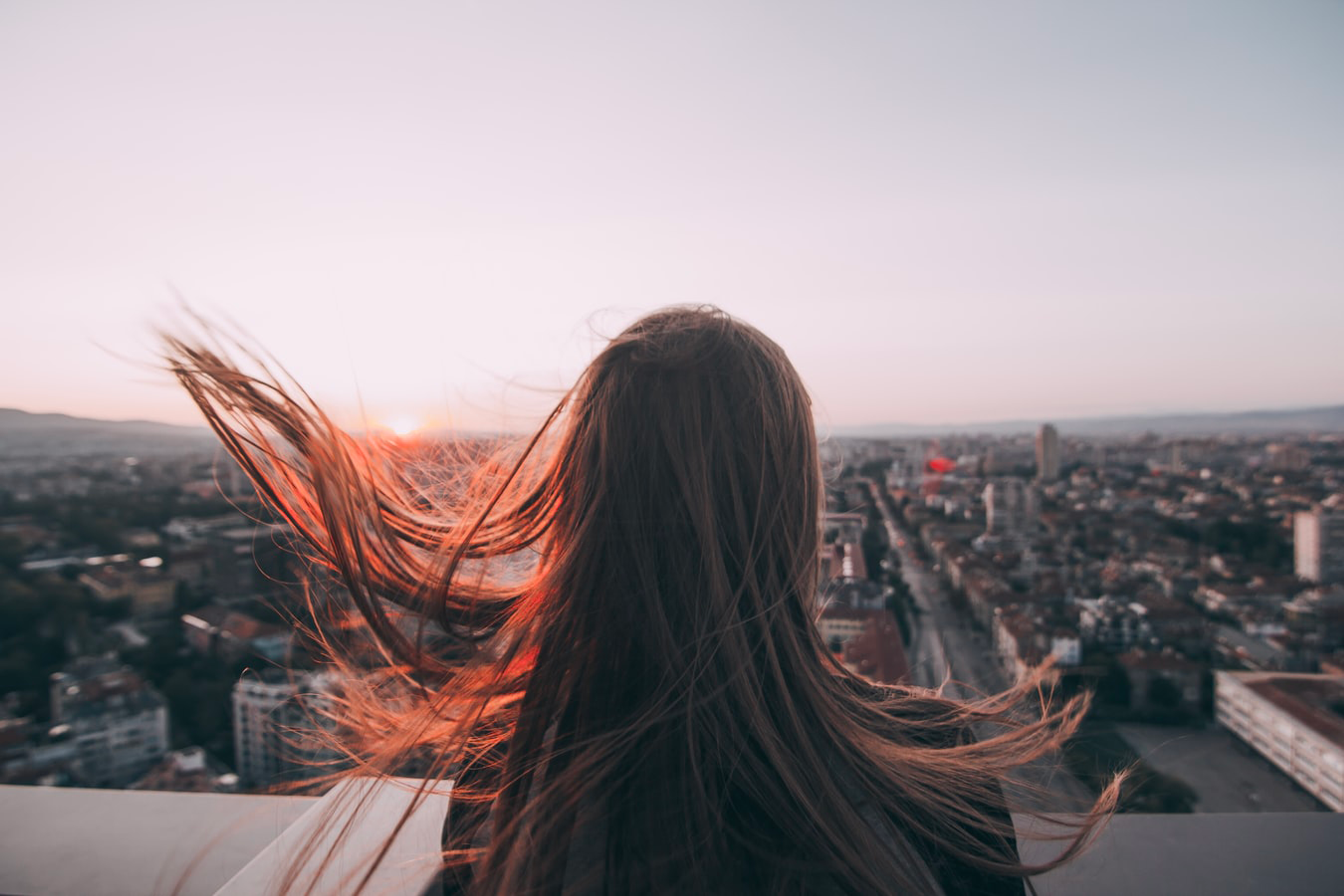 Person with long hair in the wind looking over the city