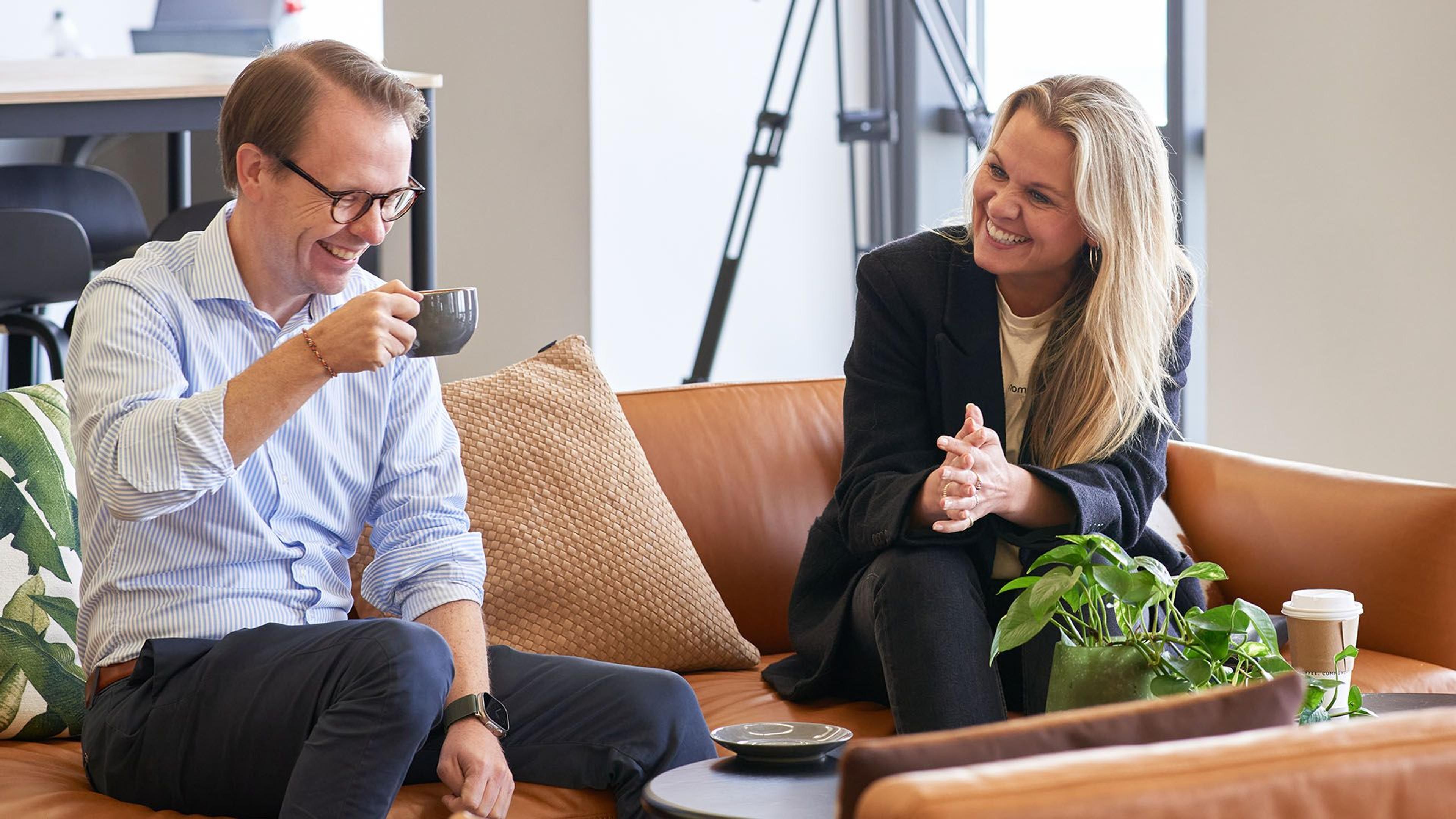 Two people in a sofa talking business and laughing