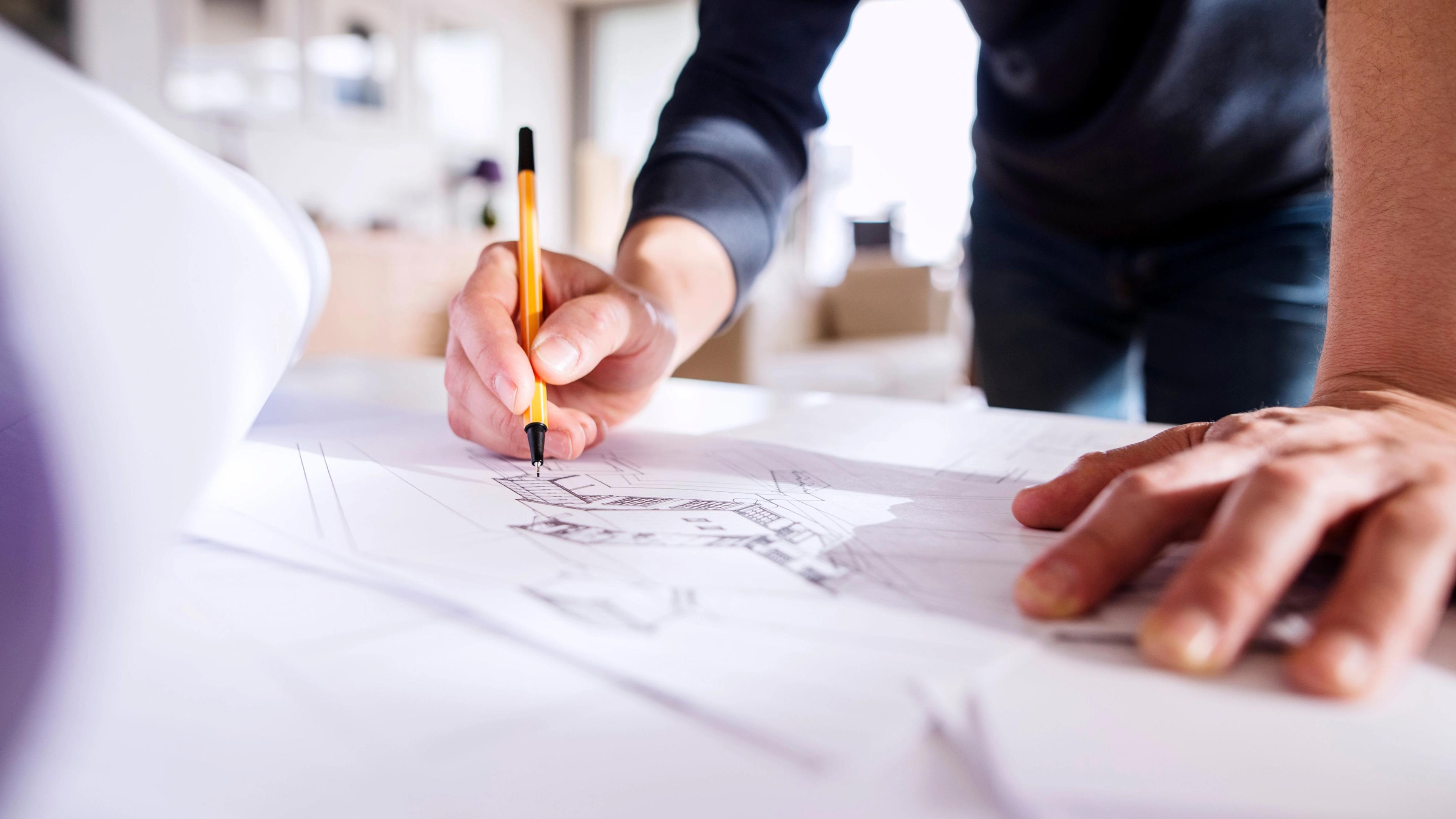 Close up of the hands of someone drawing a house