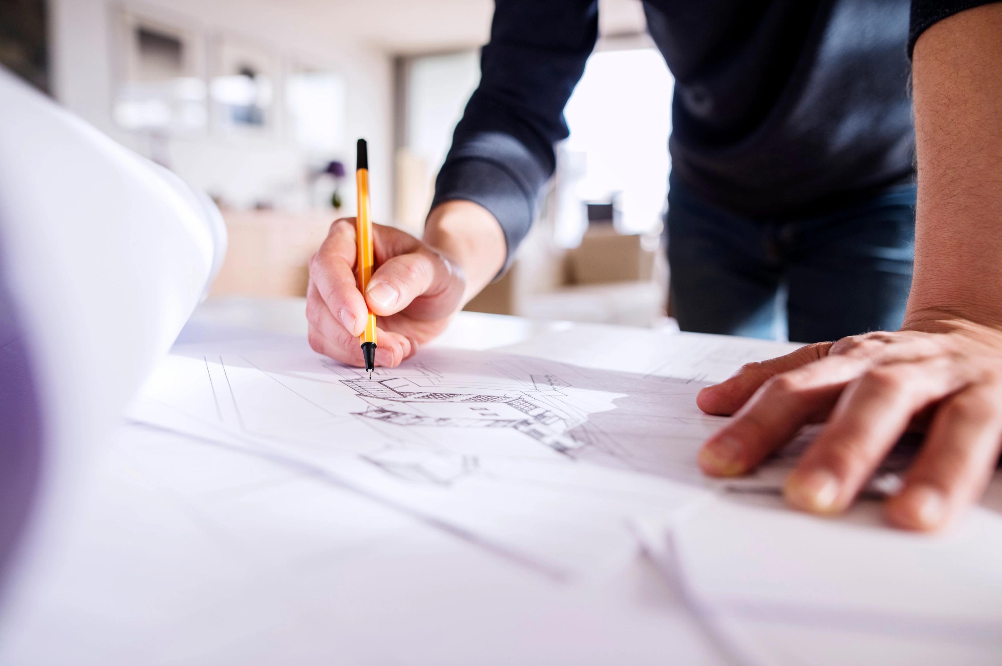 Close up of the hands of someone drawing a house