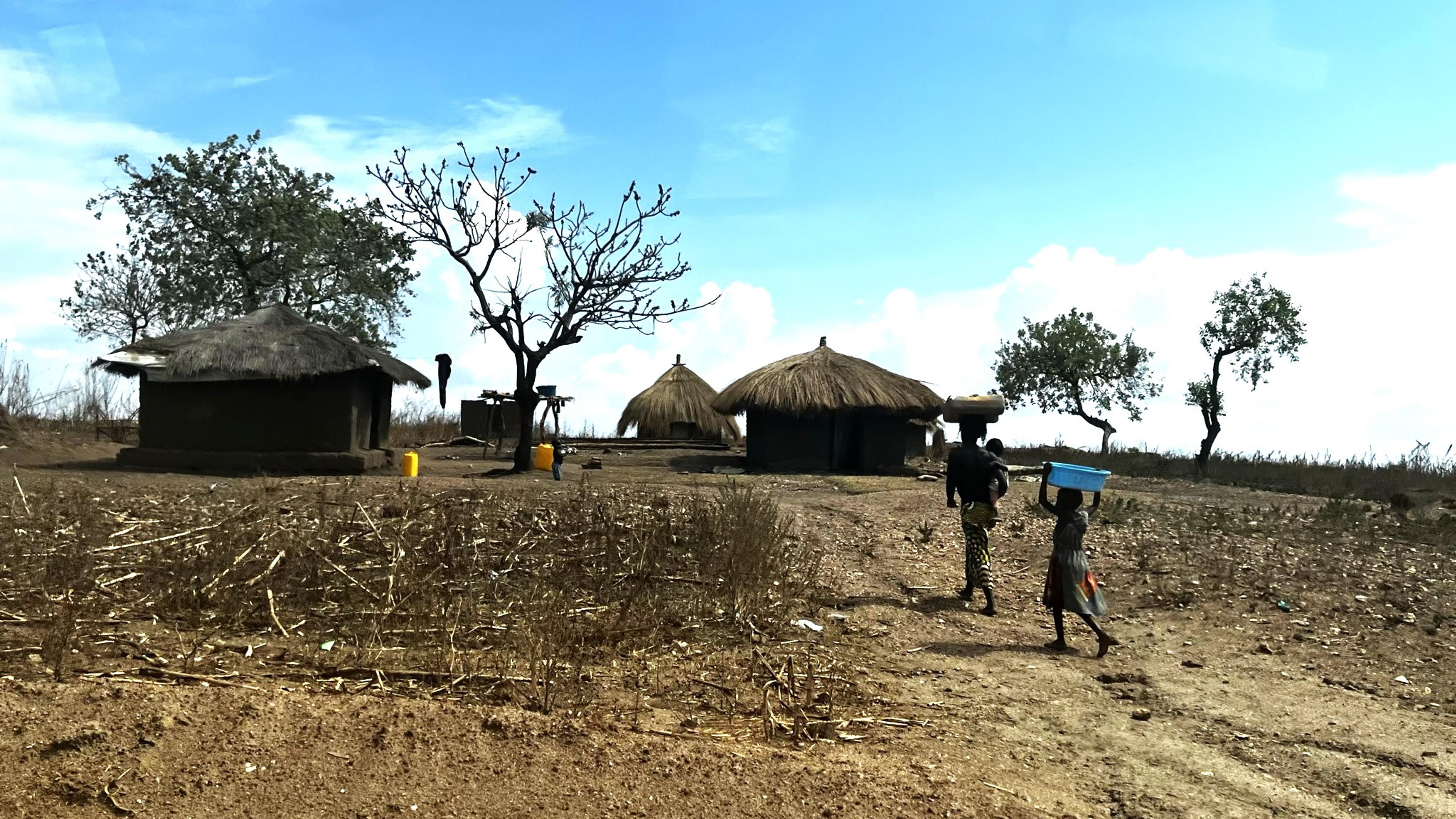 Two people walking towards their shelter in Uganda.