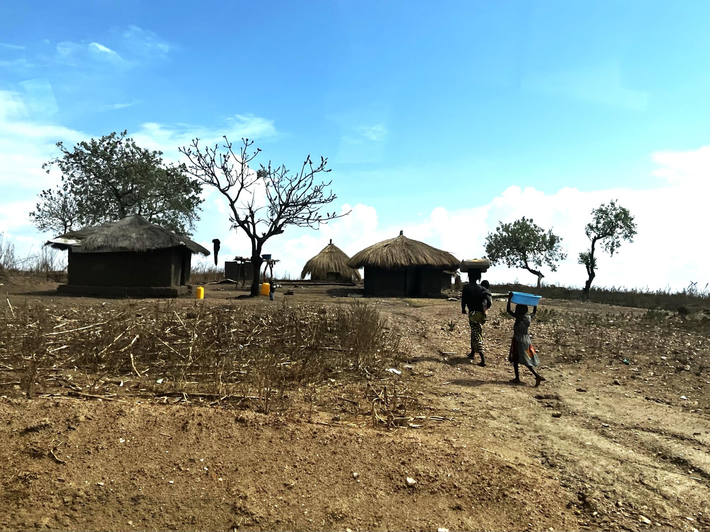 Two people walking towards their shelter in Uganda.