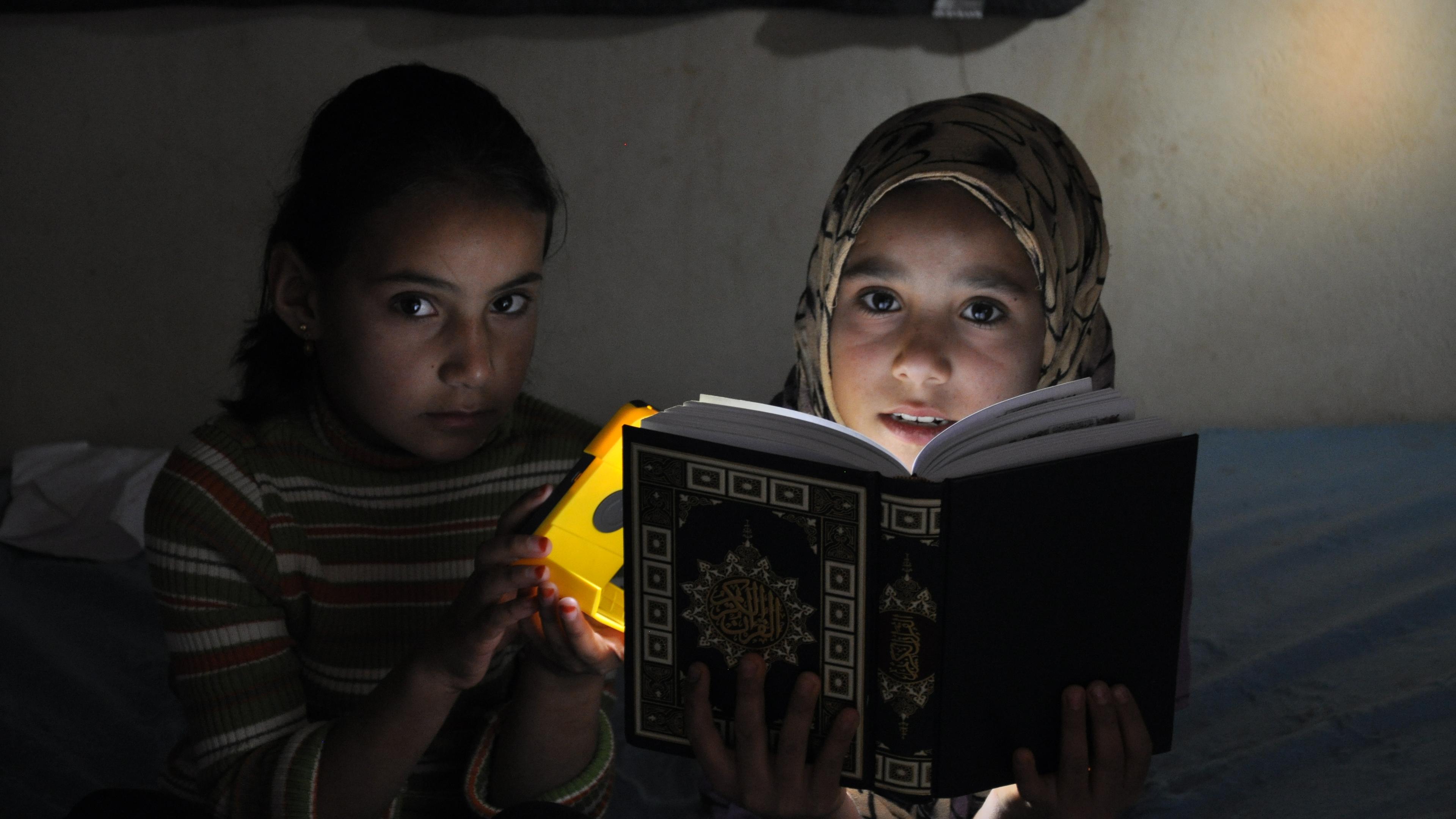 Girls using night light to read a book.