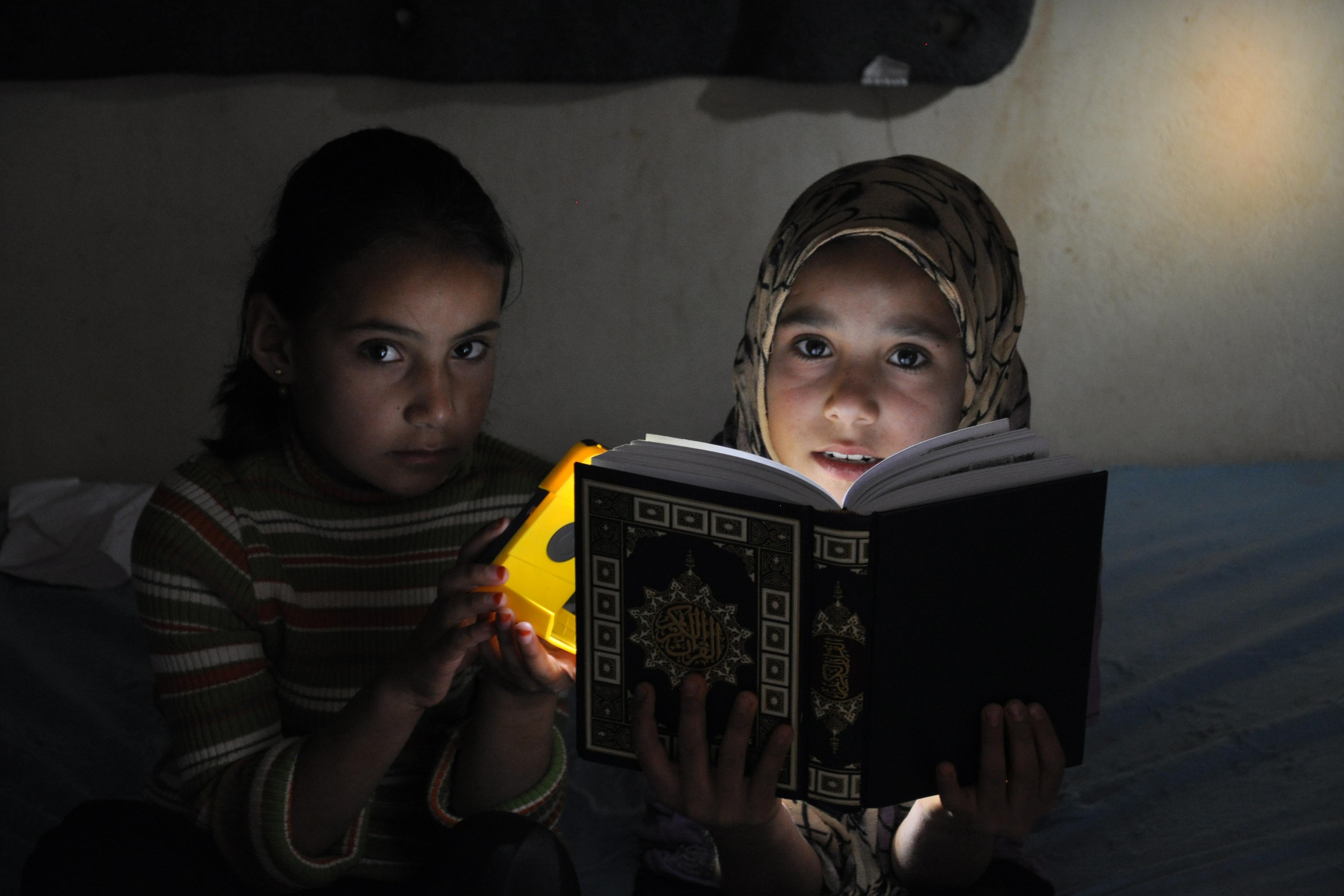 Girls using night light to read a book.