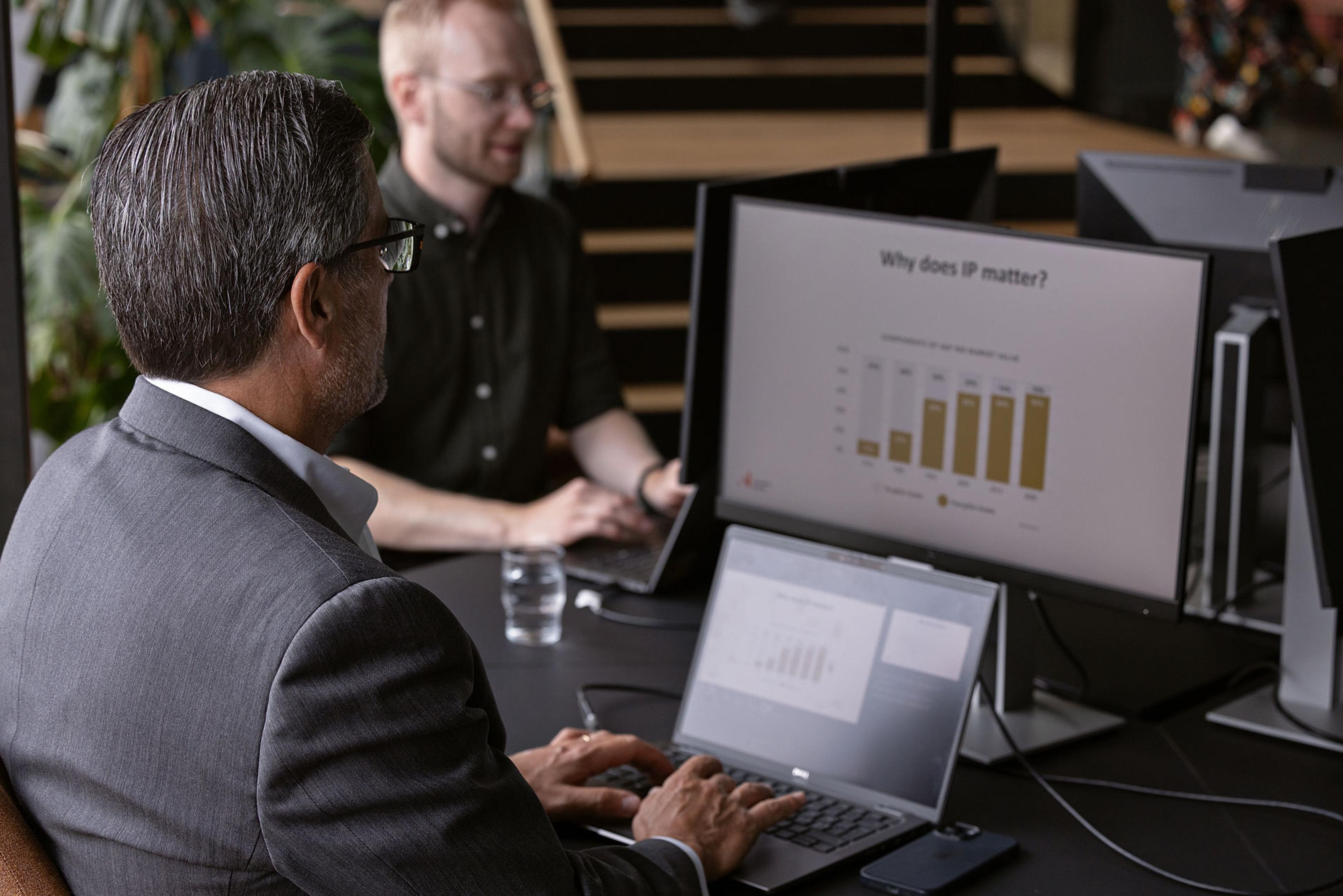 En mann foran en pc-skjerm med grafer