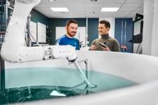 To personer som står ved en vanntank med en sensor i hånda