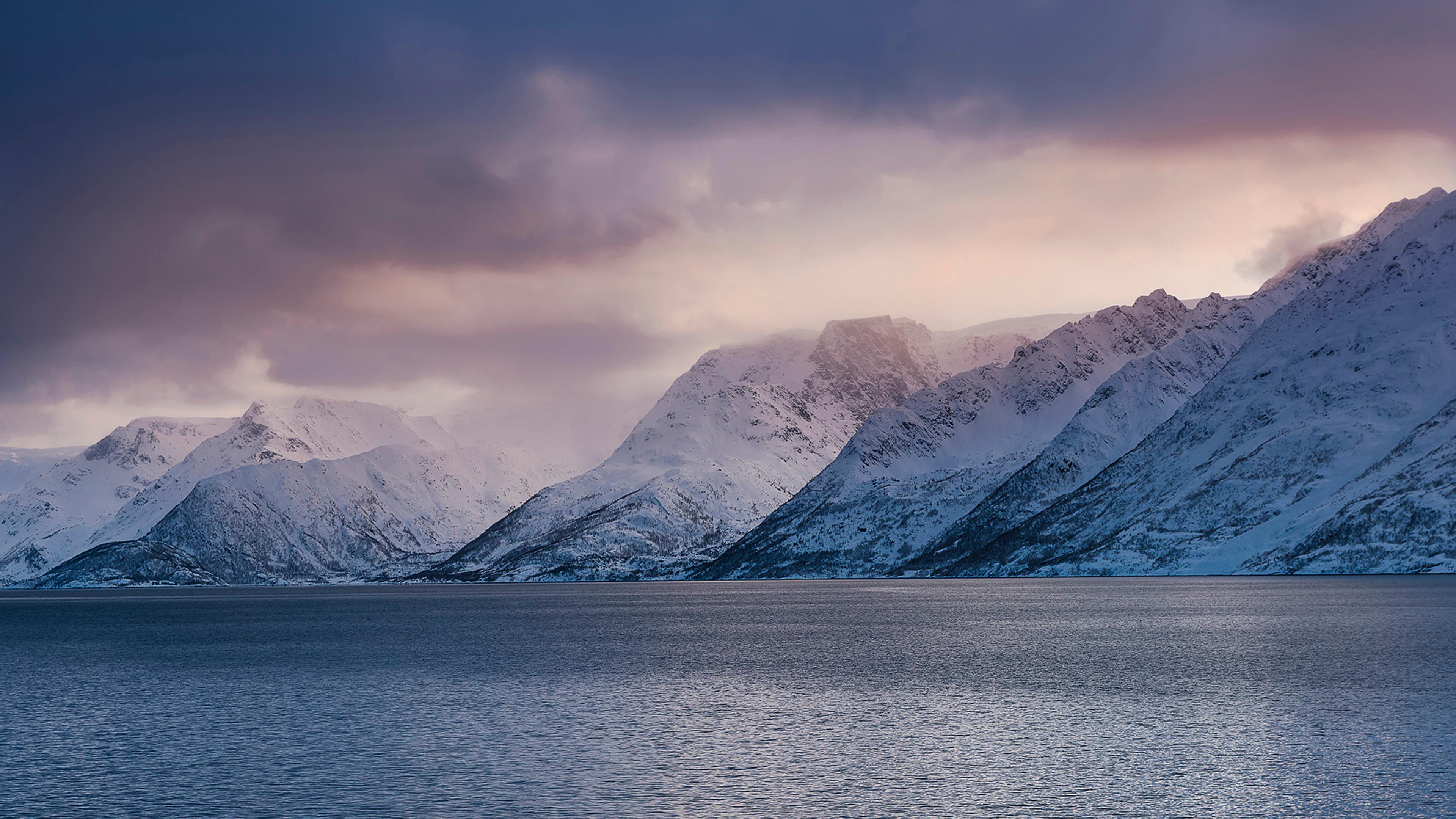 Snødekkede fjell som går ned i havet