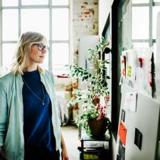 Kvinne ser på ark og lapper som er hengt opp på en tavle