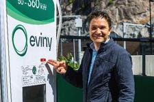 Mann som står ved en ladestasjon for elbiler