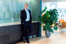 Administrerende direktør Håkon Haugli i Innovasjon Norge står smilende foran en grønn vegg på hovedkontoret.