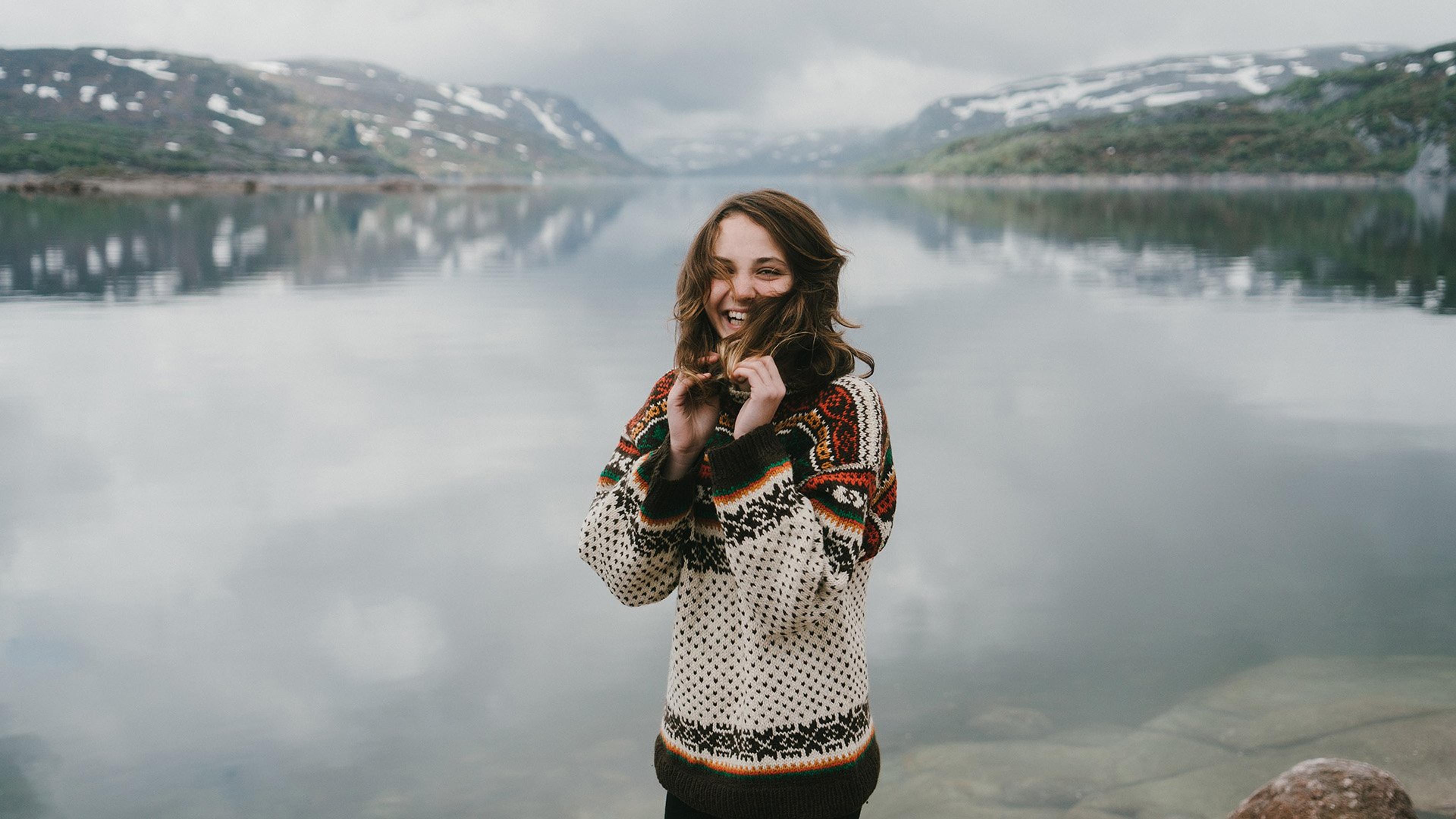 Jente med ullgenser som koser seg ute ved en fjord